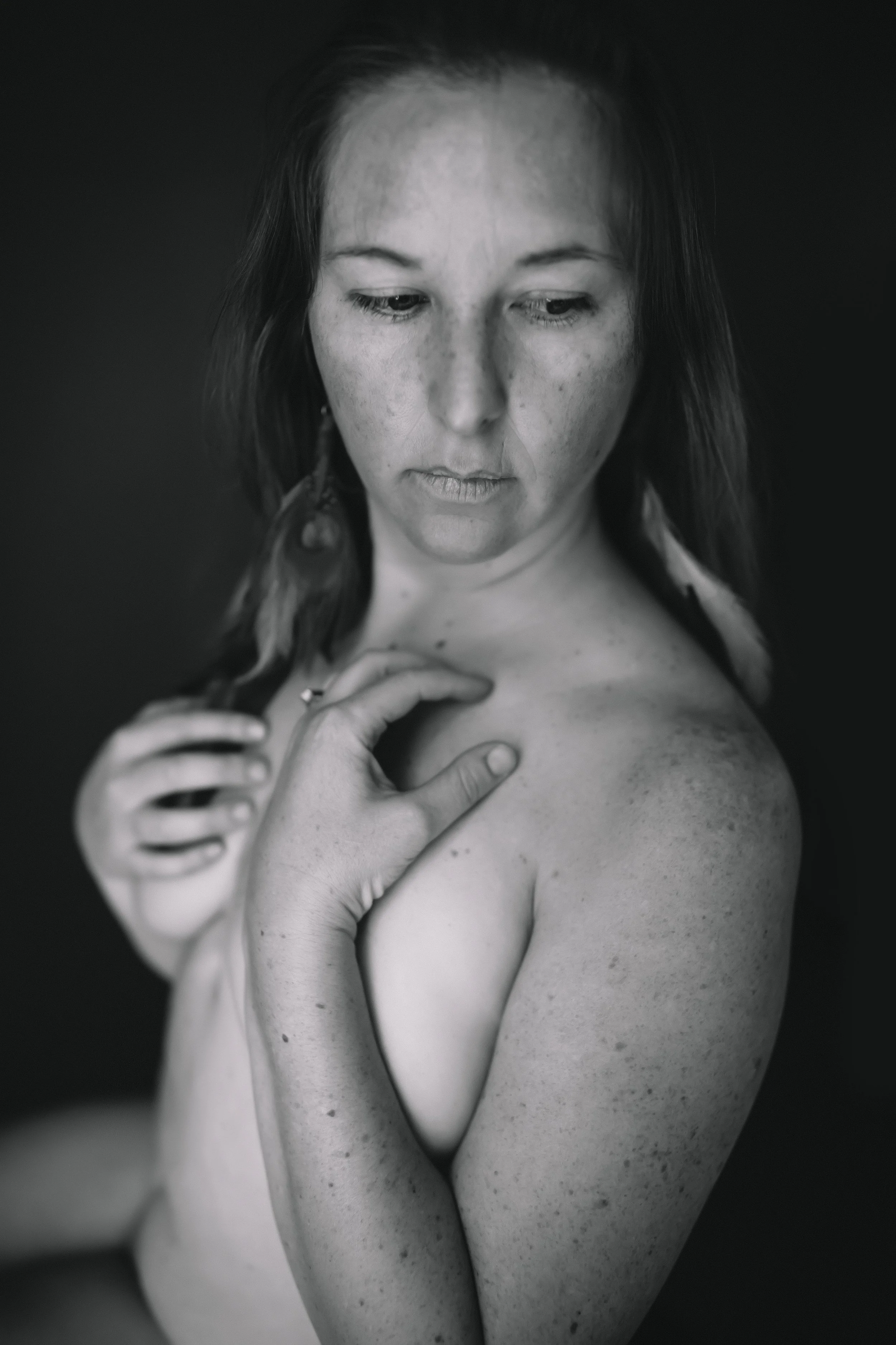 An intimate black and white close-up portrait of a woman cradling her own shoulder, captured as part of The Raw Project by Emily Scott in Beaufort, South Carolina.