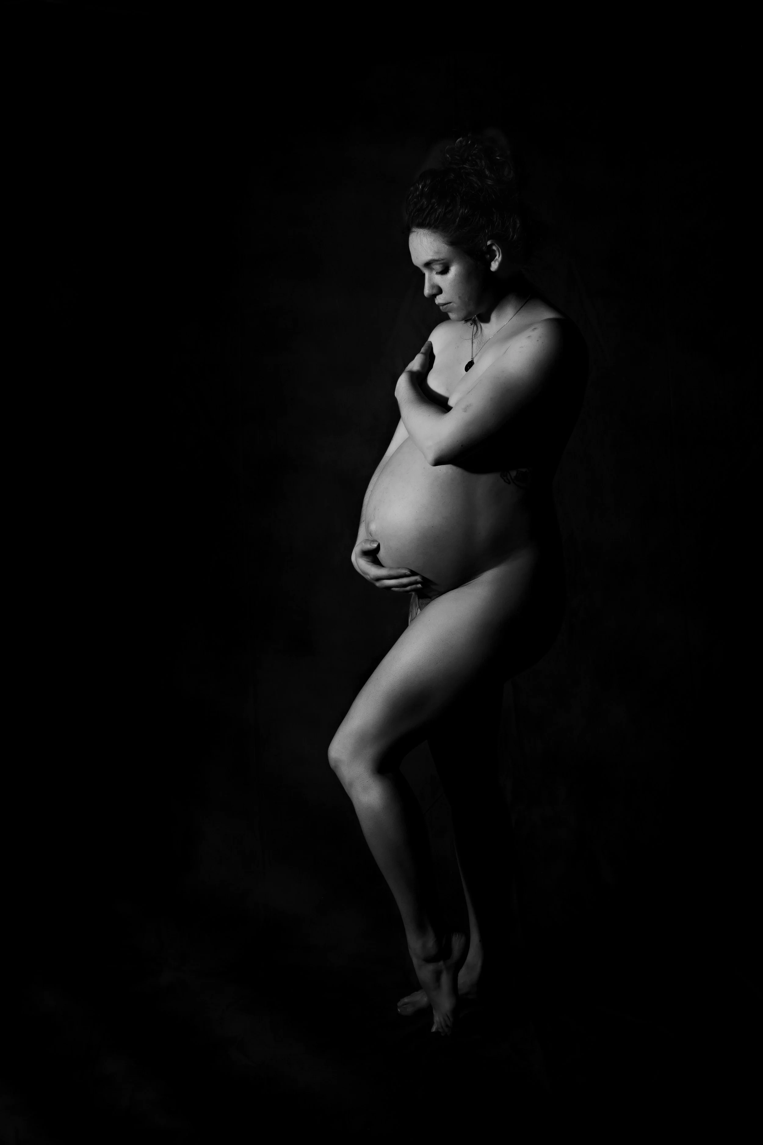 Stunning black and white maternity fine art portrait of a pregnant woman in profile cradling her belly, Boudoir by Emily, Beaufort SC