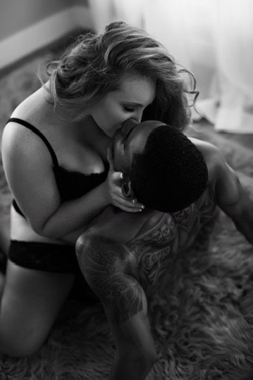 Black and white couples boudoir portrait captured mid kiss on a fur rug, Boudoir by Emily, South Carolina
