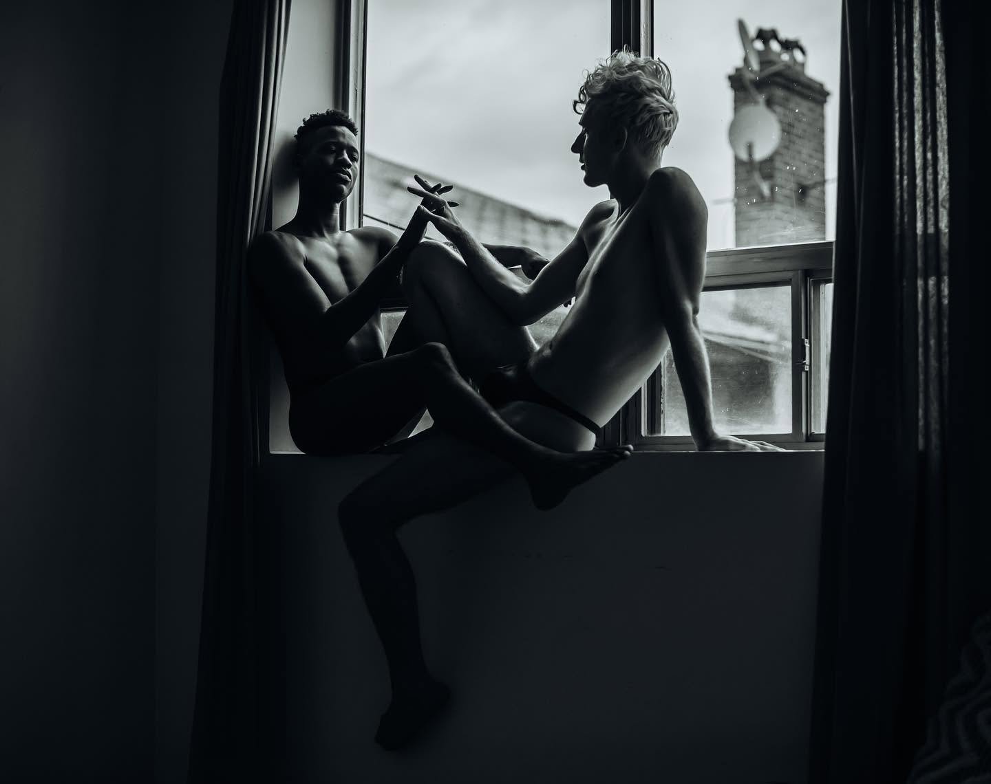 A tender black and white couples boudoir portrait of two partners lying together, photographed at Bay Street Studios in Beaufort, SC.