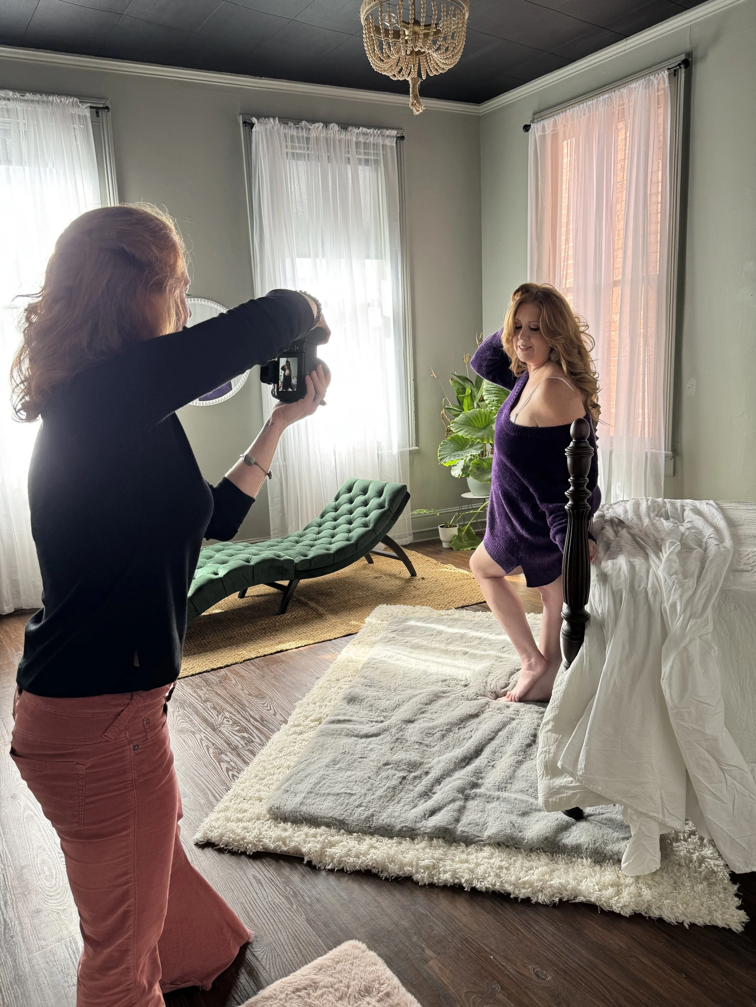 Behind the scenes of a boudoir photography session with Emily Scott at Bay Street Studios in historic downtown Beaufort, SC, Emily guiding a client near the four-poster bed in beautiful natural light.