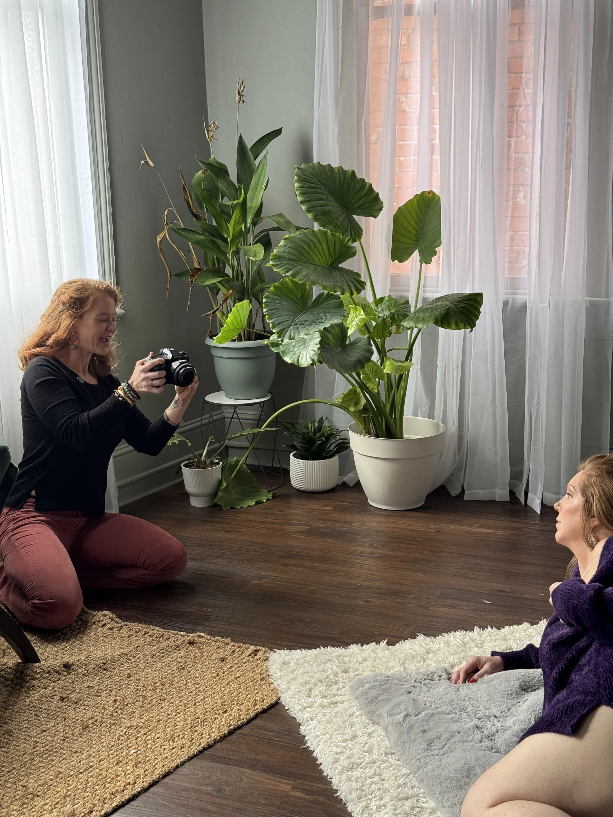 Emily Scott at work on the studio floor, photographing a client reclining on a plush rug during a boudoir session at Bay Street Studios in Beaufort, SC.