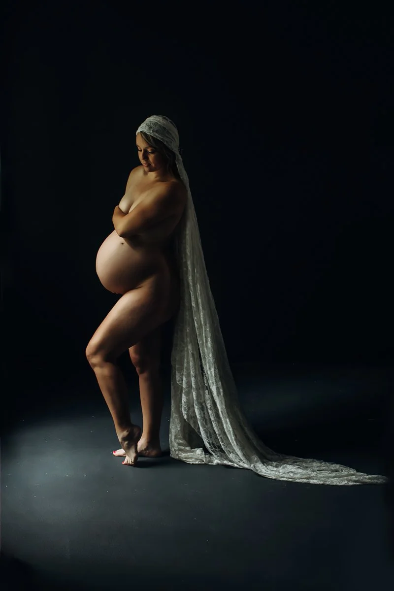 A tender fine art maternity boudoir portrait of a pregnant woman with a flowing lace veil, photographed at Bay Street Studios in Beaufort, SC.