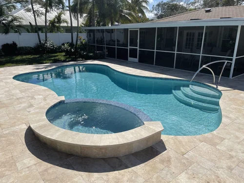 Travertine paver deck around a freeform pool and spa in Jupiter, FL