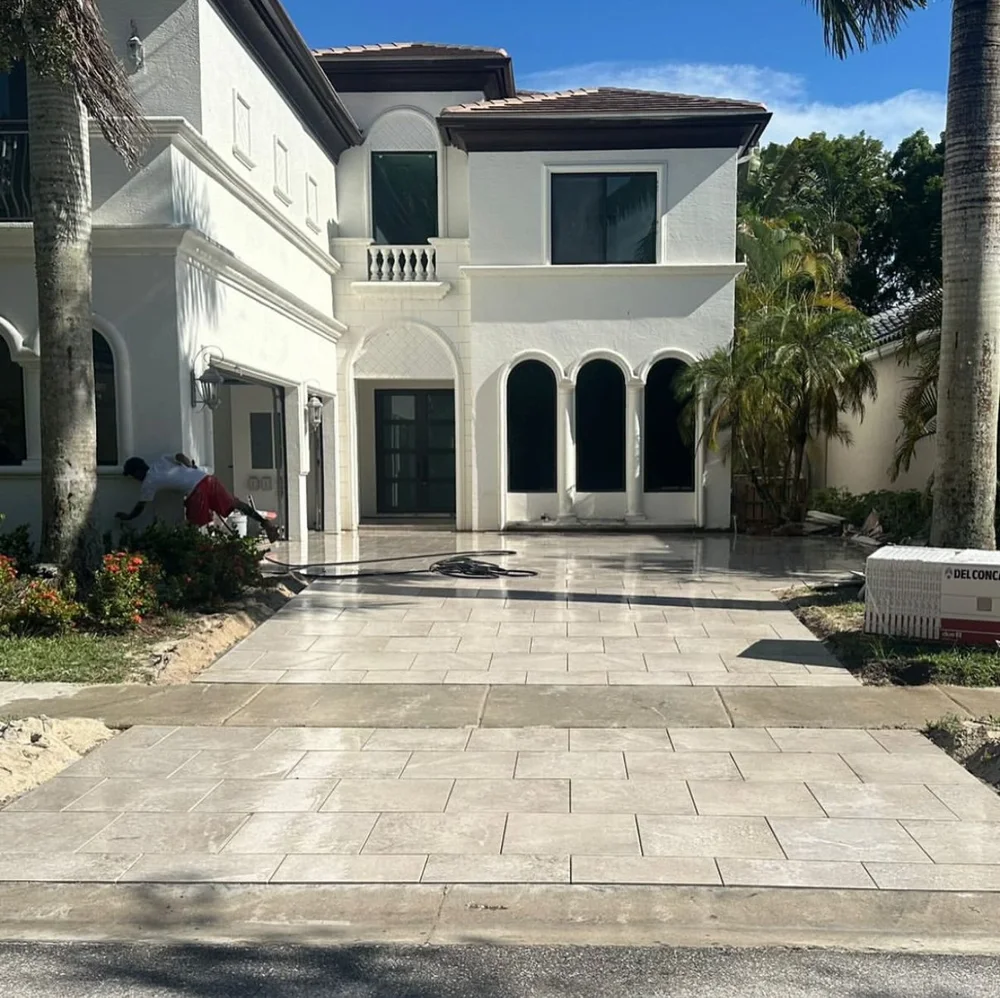 Light natural-stone paver driveway being installed at a two-story home by Big Cat Hardscapes in Palm Beach Gardens, FL