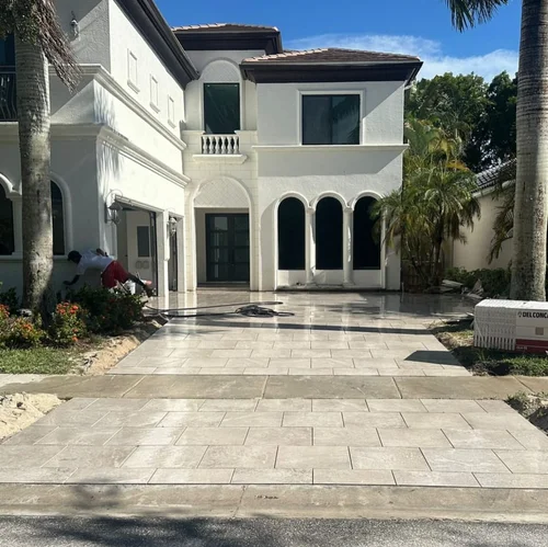 Light natural-stone paver driveway being installed at a two-story home by Big Cat Hardscapes in West Palm Beach, FL