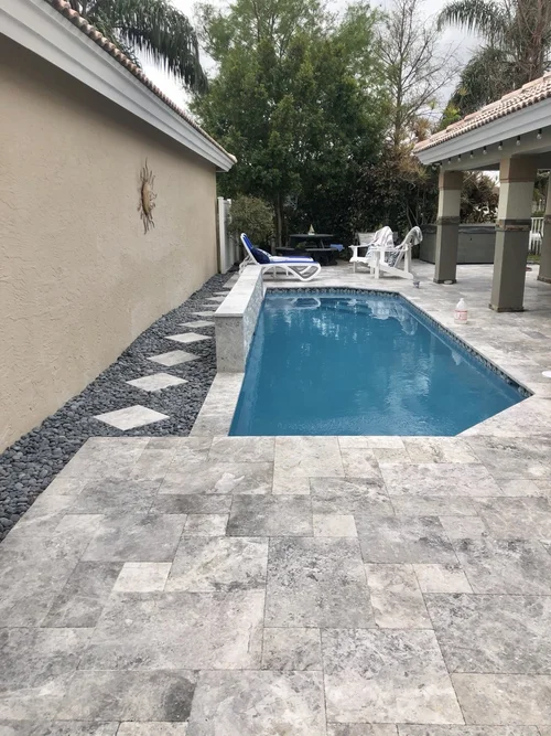 Travertine deck and stepping stones beside a pool in West Palm Beach, FL