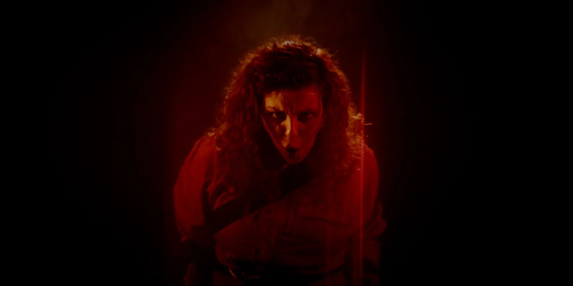 mujer pelijora con expresión de enojo o ira, en un entorno oscuro, iluminada con luz roja en el rodaje del videoclip el martillo de las brujas de la banda de Metal moderno, groove metal, metalcore y deathcore Rabia Perez en Madrid.