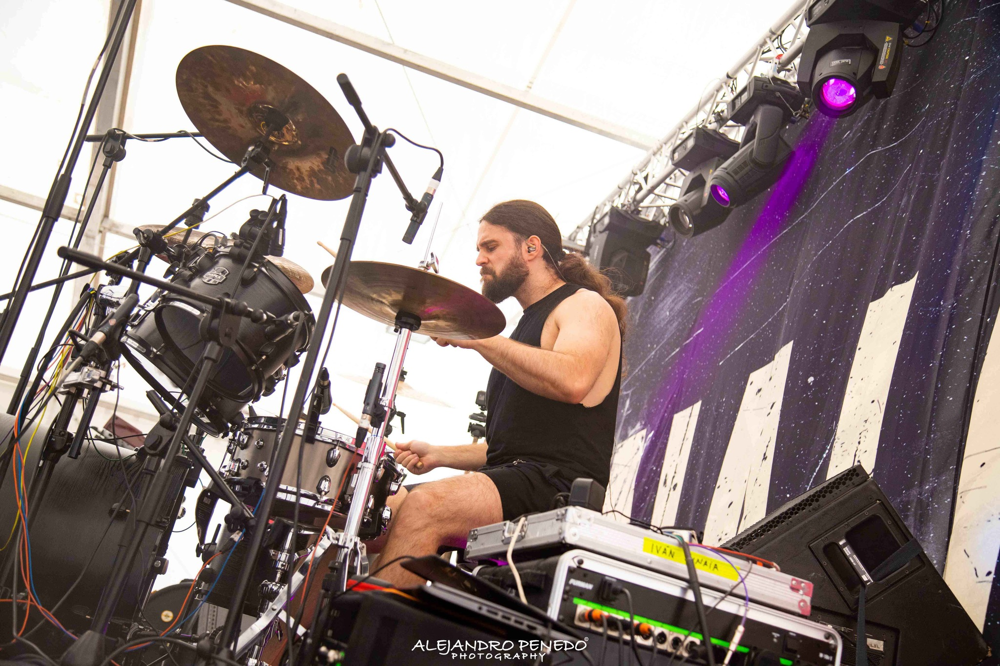 Percusionista de Metal moderno, groove metal, metalcore y deathcore tocando en un escenario de madrid con equipo musical y luces de escenario.