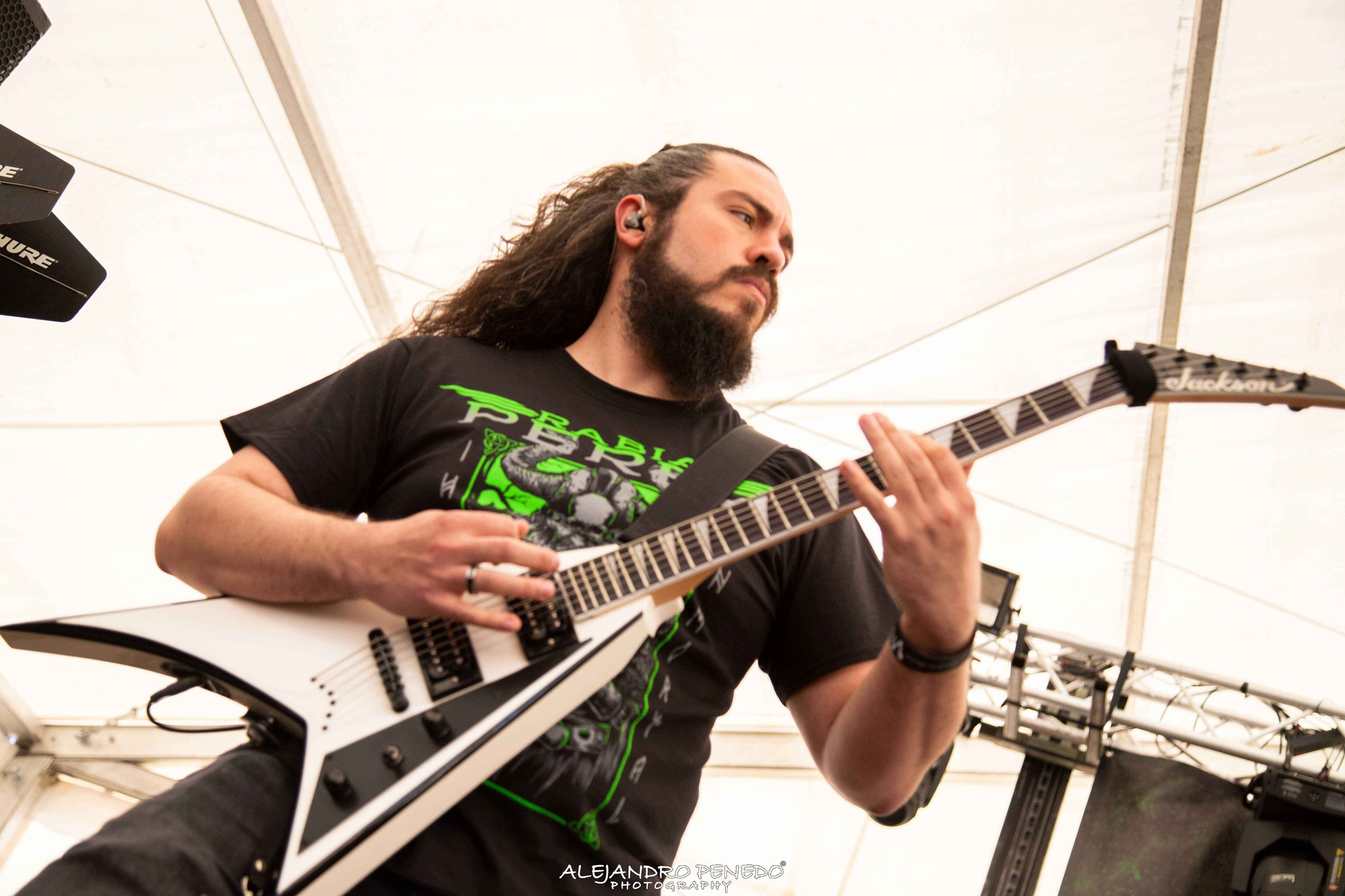 Hombre tocando Metal moderno, groove metal, metalcore y deathcore en una guitarra eléctrica jackson en un escenario bajo una carpa blanca en Madrid.