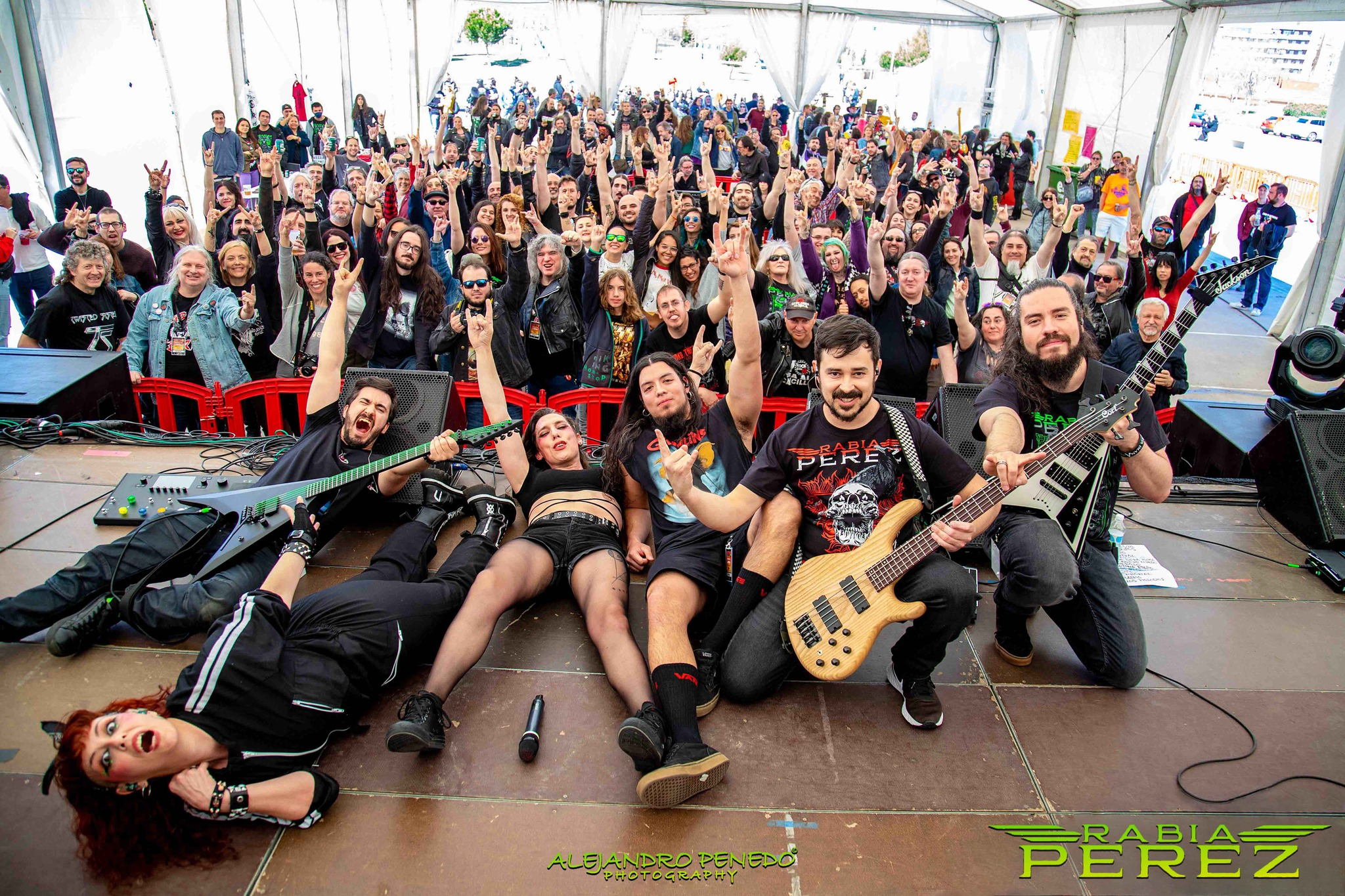 Una banda de rock posando en el escenario frente a un público numeroso en un evento de Metal moderno, groove metal, metalcore y deathcore en Madrid al aire libre, con muchos espectadores levantando las manos y haciendo signos de rock.