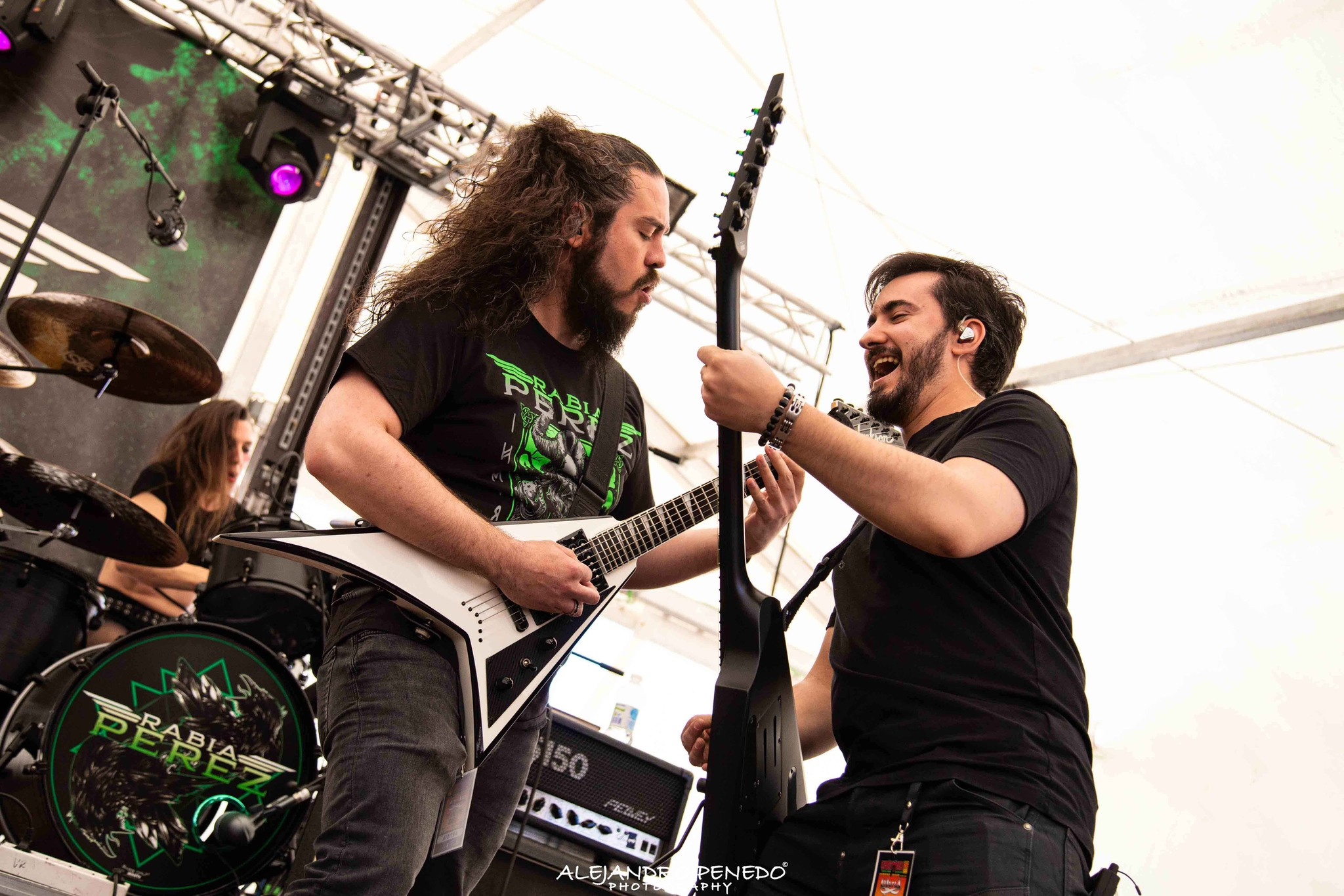 Dos músicos de Metal moderno, groove metal, metalcore y deathcore en un escenario de madrid tocando guitarras, uno con barba y otro con cabello rizado, en un concierto al aire libre con iluminación y equipo de música.