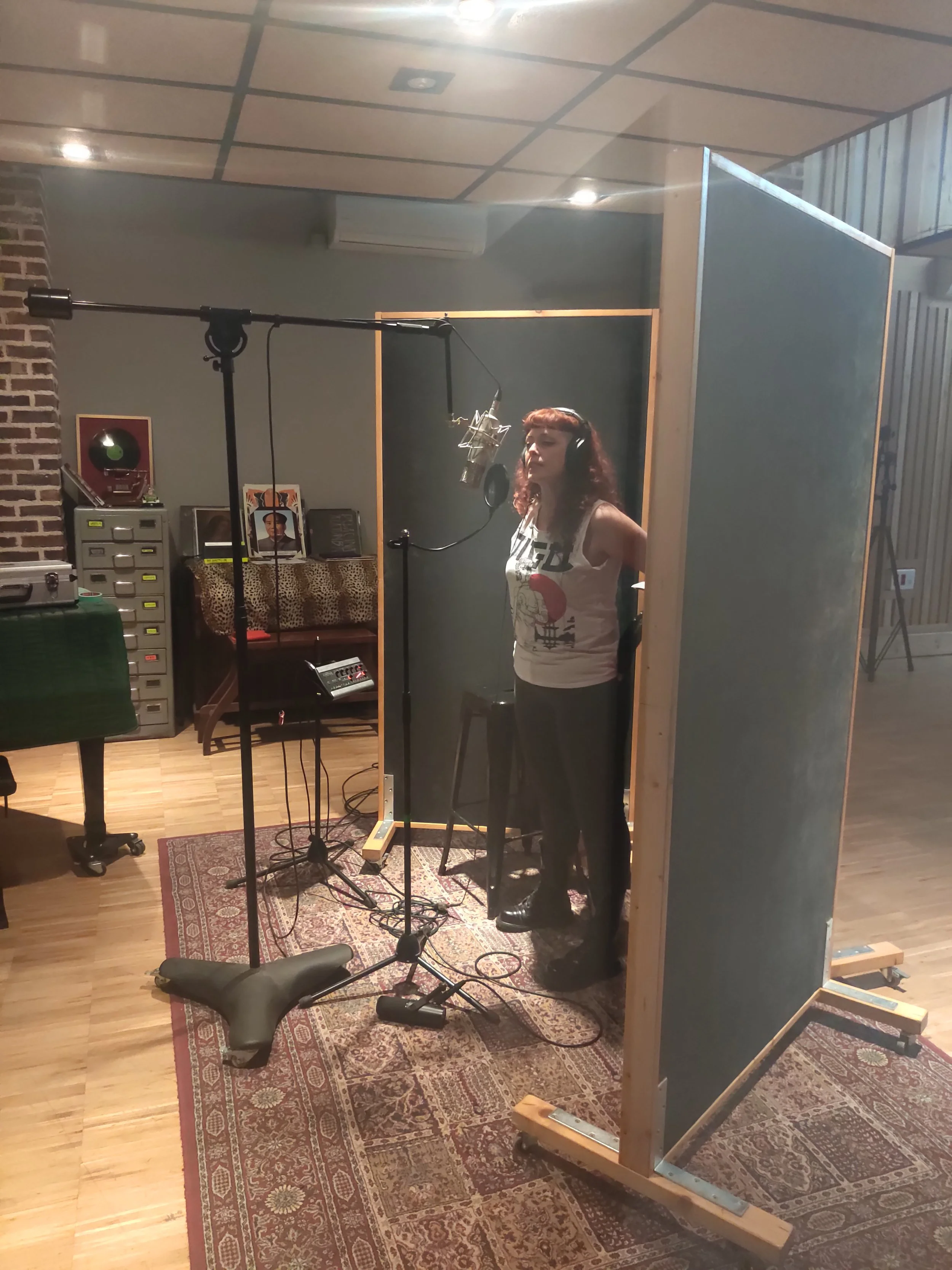 Madrid. Metal moderno, metalcore, Groove metal y deathcore. Una mujer en un estudio de grabación, frente a un micrófono, con un cabina aislante a su alrededor.