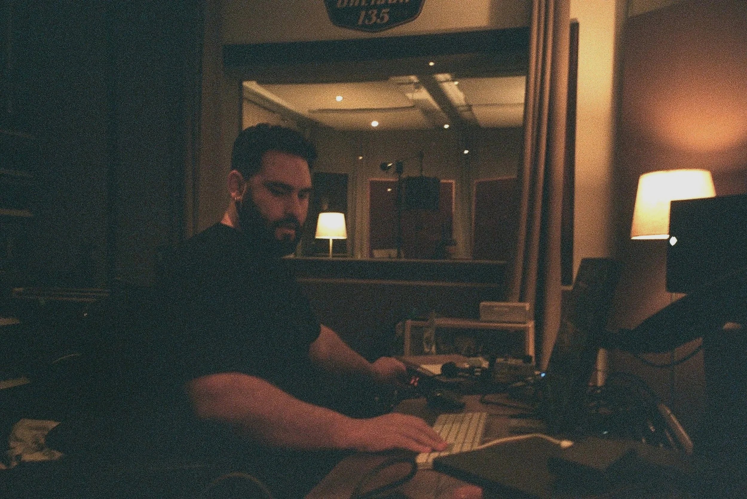 Madrid. Metal moderno, metalcore, Groove metal y deathcore. Hombre trabajando en un estudio con equipo de audio y computadora en un ambiente con iluminación cálida.