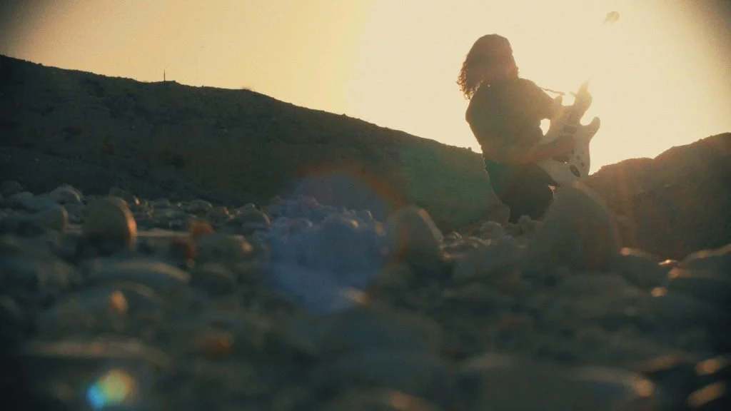 Guitarrista fundador de la banda de madrid de Metal moderno, groove metal, metalcore y deathcore Rabia Perez, Gabriel Peñasco tocando la guitarra en un paisaje natural durante el atardecer.