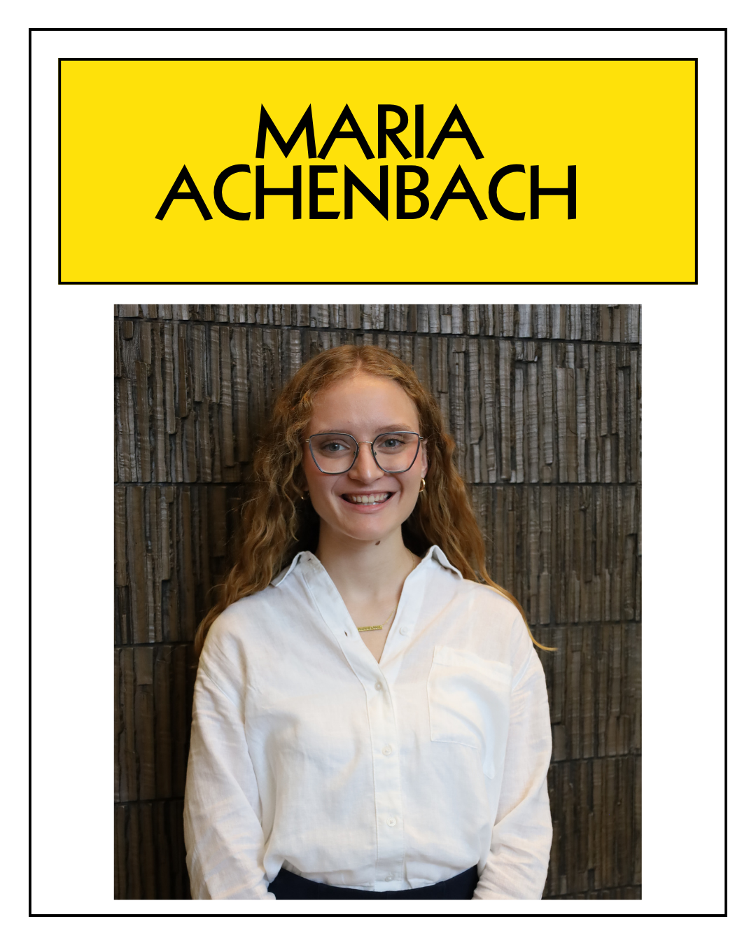 A woman with curly red hair and glasses smiling in front of a wooden wall, wearing a white blouse.