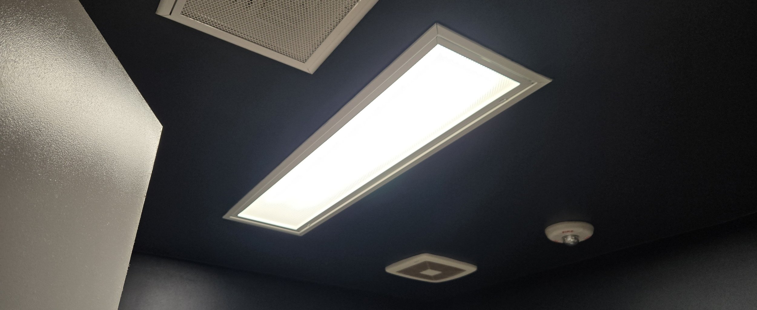 Ceiling with rectangular light fixture, smoke detector, and air vent.