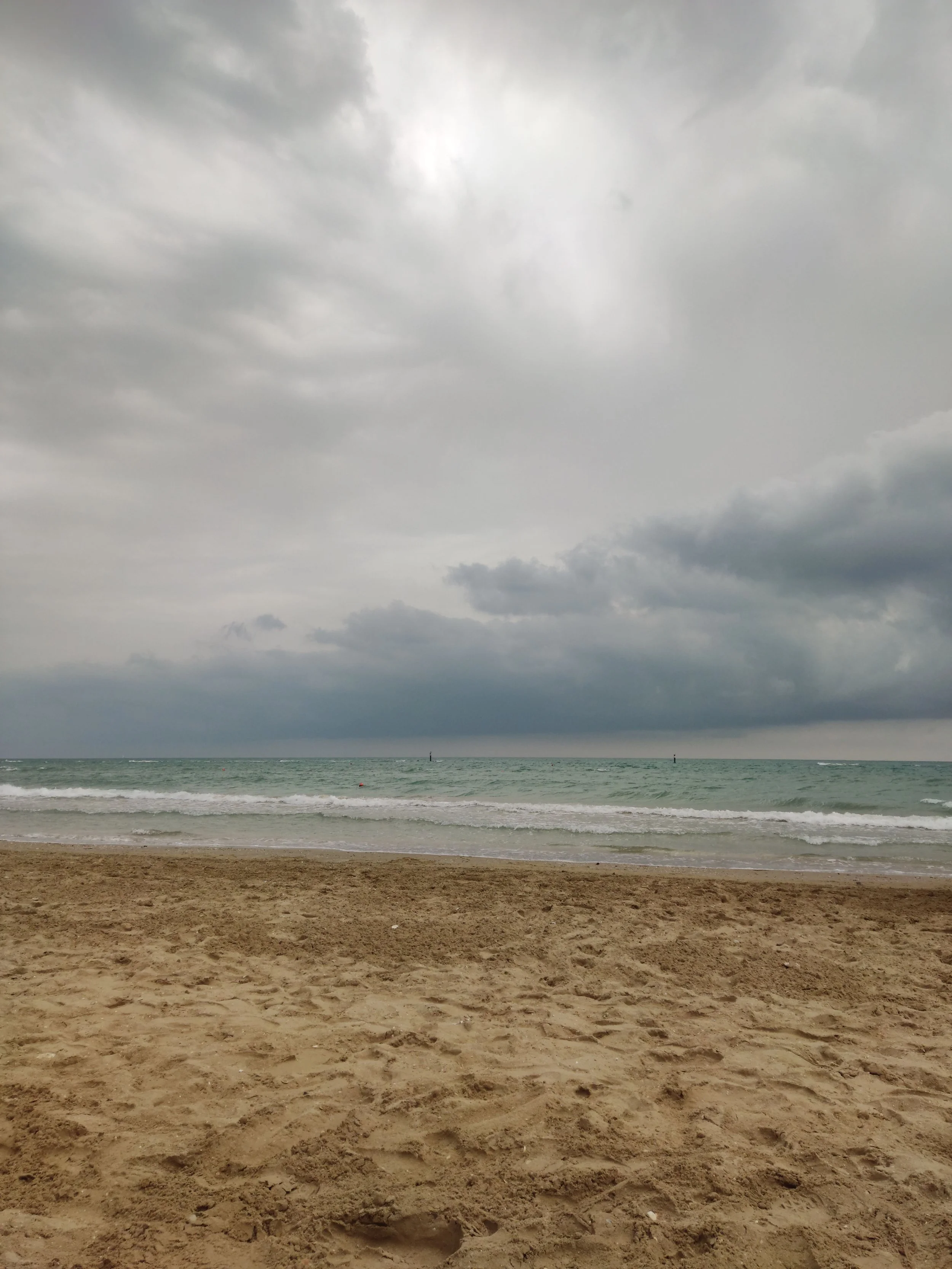 Storm clouds over ocean waves and a sandy beach.
