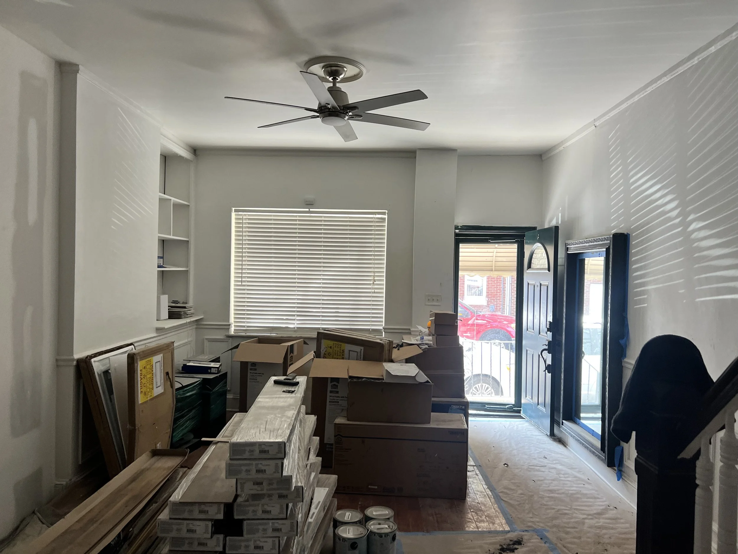 Room under renovation with boxes, packages, and supplies, partially obstructing the living area.