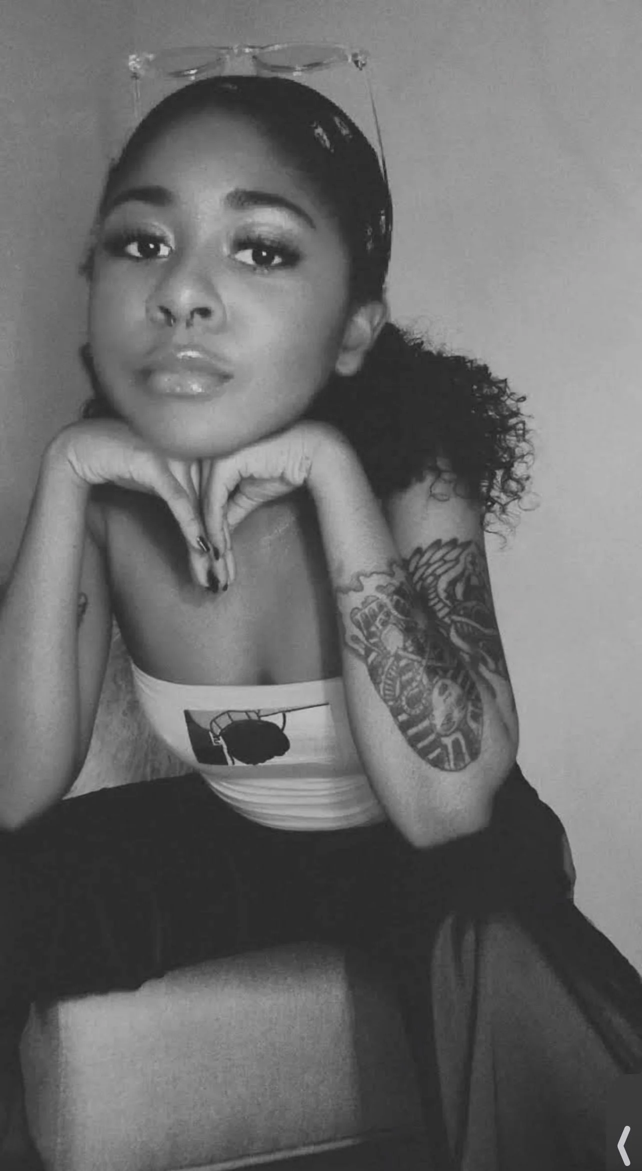 Portrait photograph of artist Azareah York featuring Egyptian-inspired tattoos and a signature pose with her hands supporting her head.