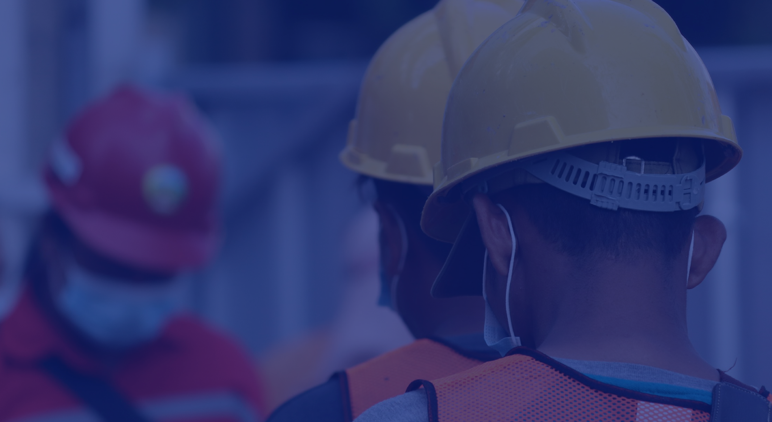 Grupo de trabajadores con cascos de seguridad y mascarillas en un entorno de construcción.