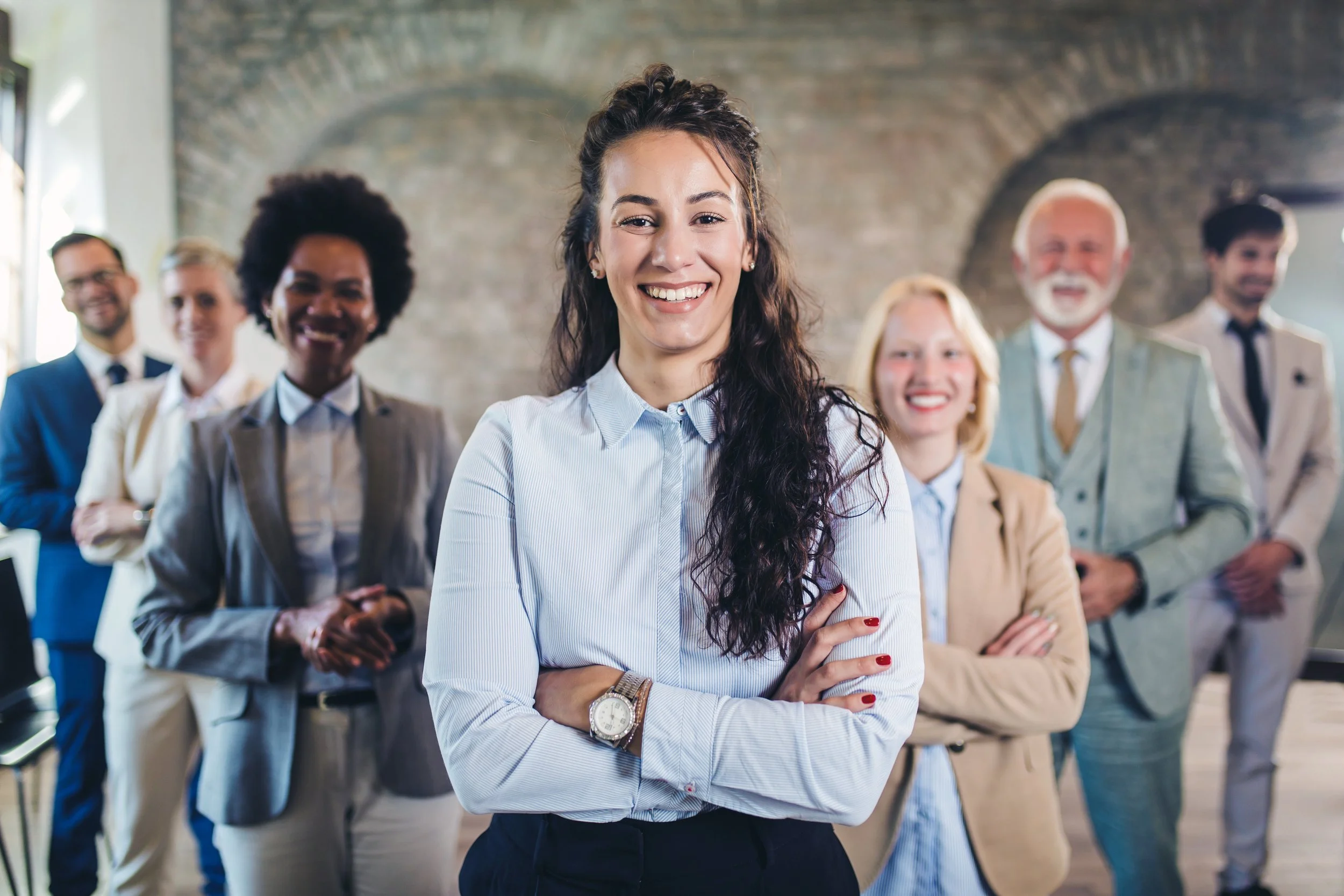 Professional woman with her arms crossed and others blurred in the background