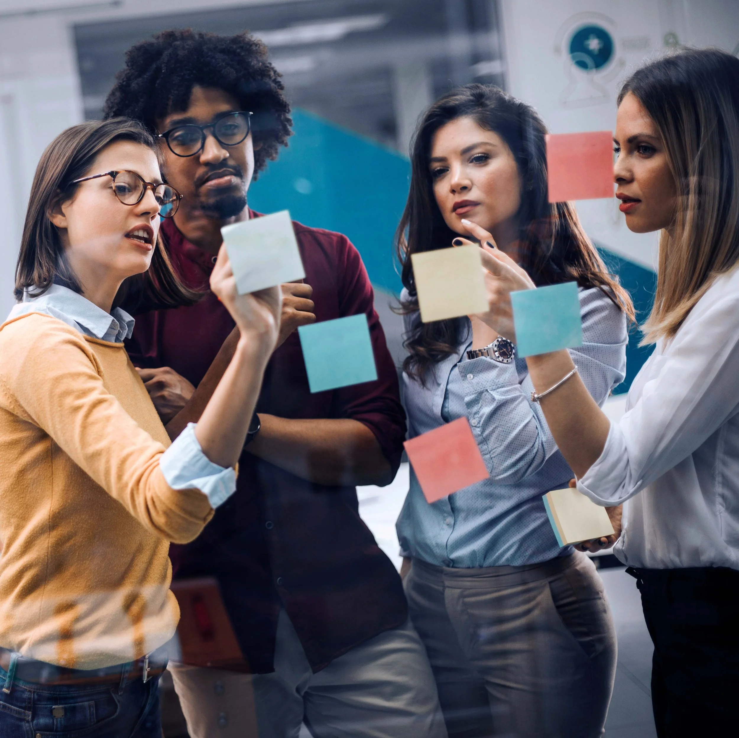 team members working with post it notes on a glass wall