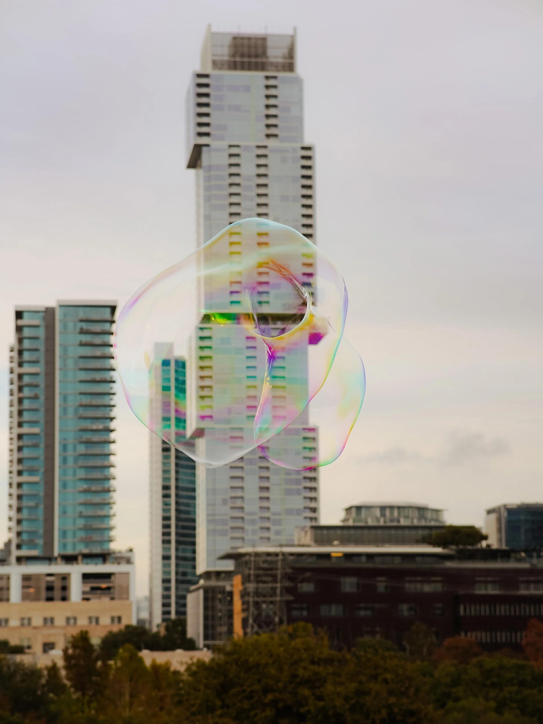 A bubble floating in front of tall skyscrapers in an urban cityscape.