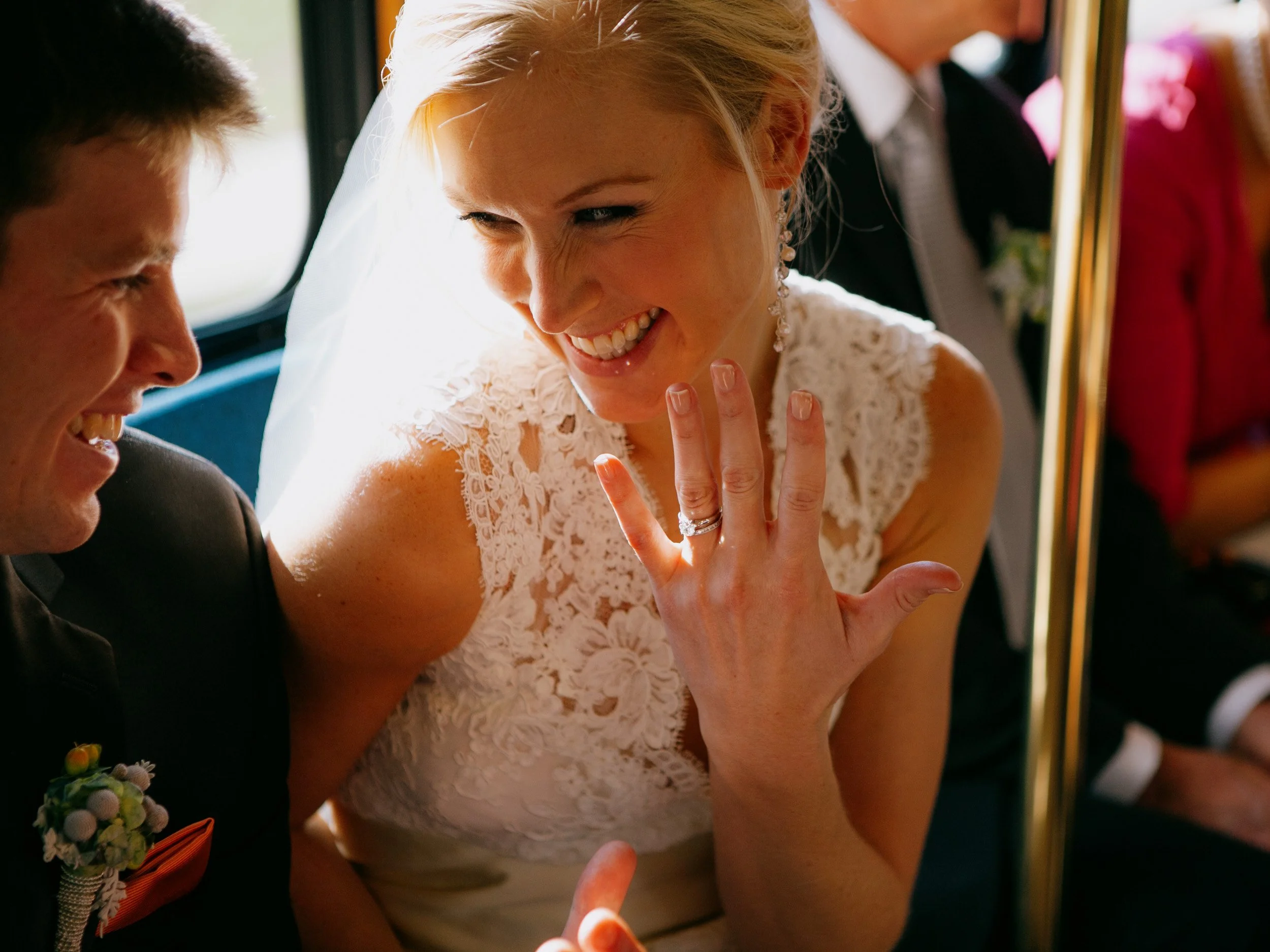 A bride and groom smiling and sharing a joyful moment on a bus during their wedding celebration.