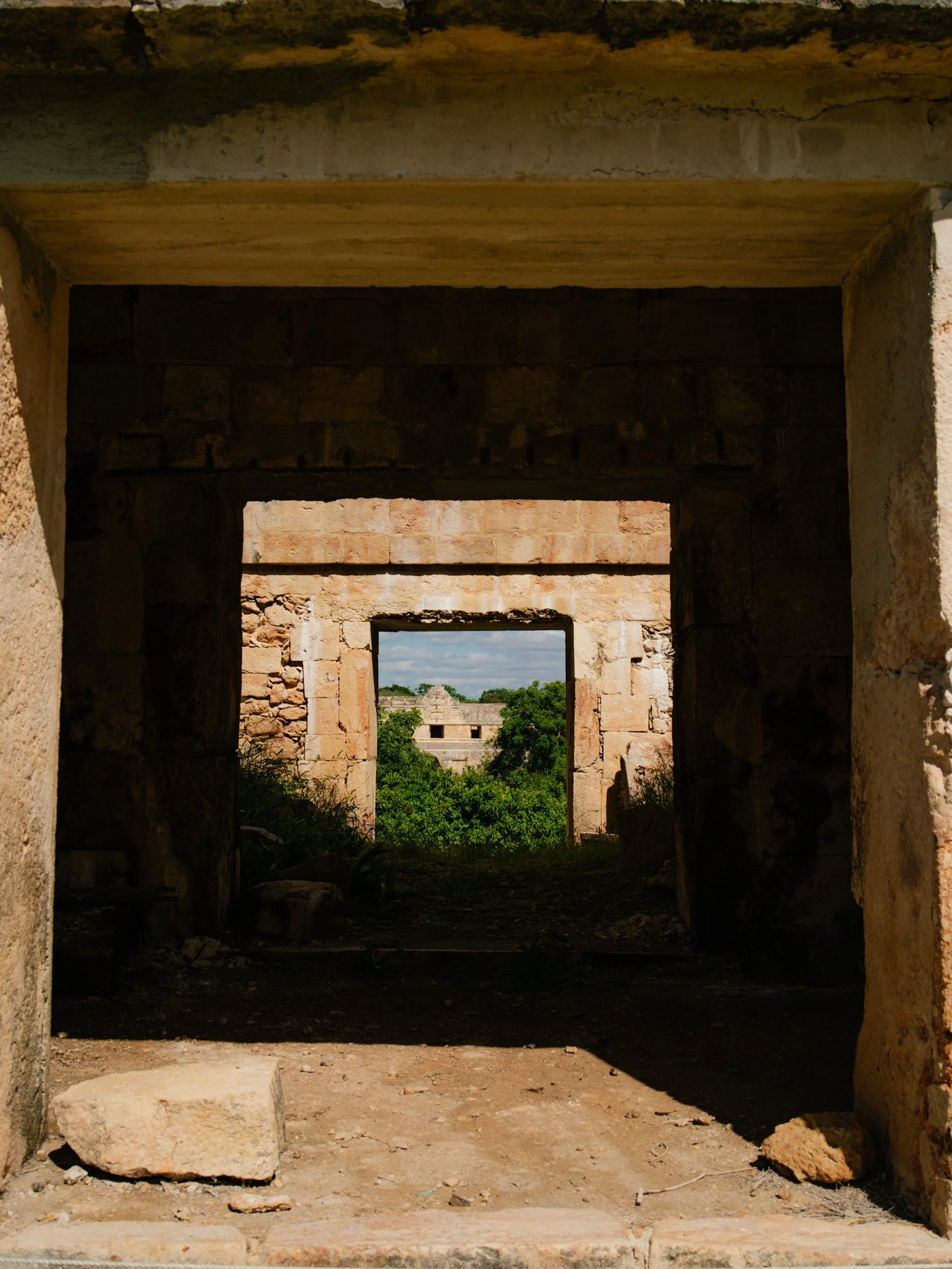 Multiple ancient stone doorways aligned, leading to a lush green landscape with ruins visible in the background.