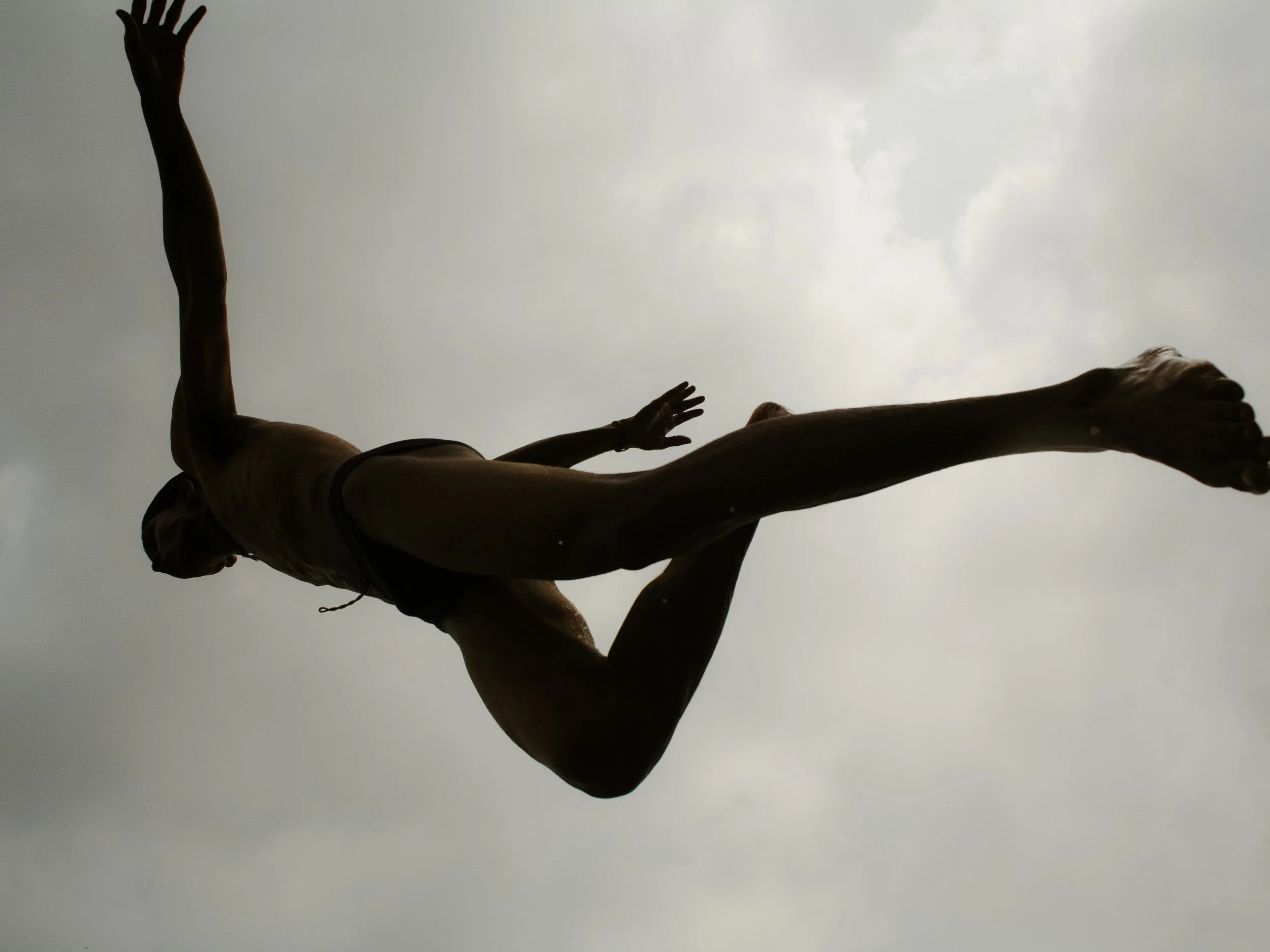 A person performing a handstand against a cloudy sky, with arms and legs extended.