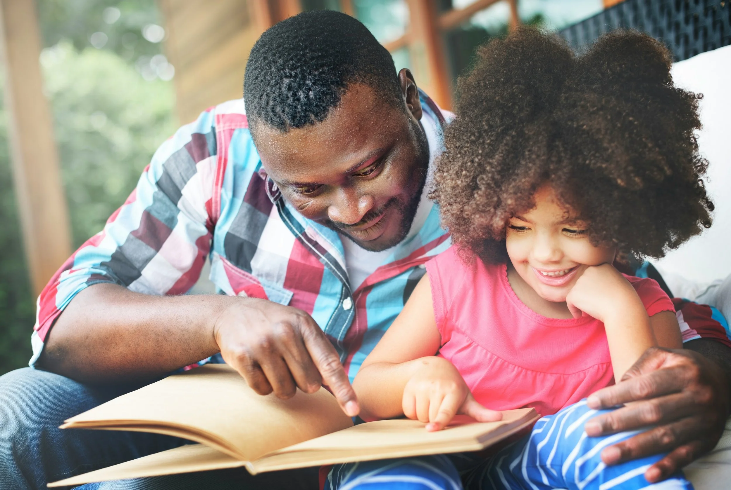 Dad and daughter read together outside