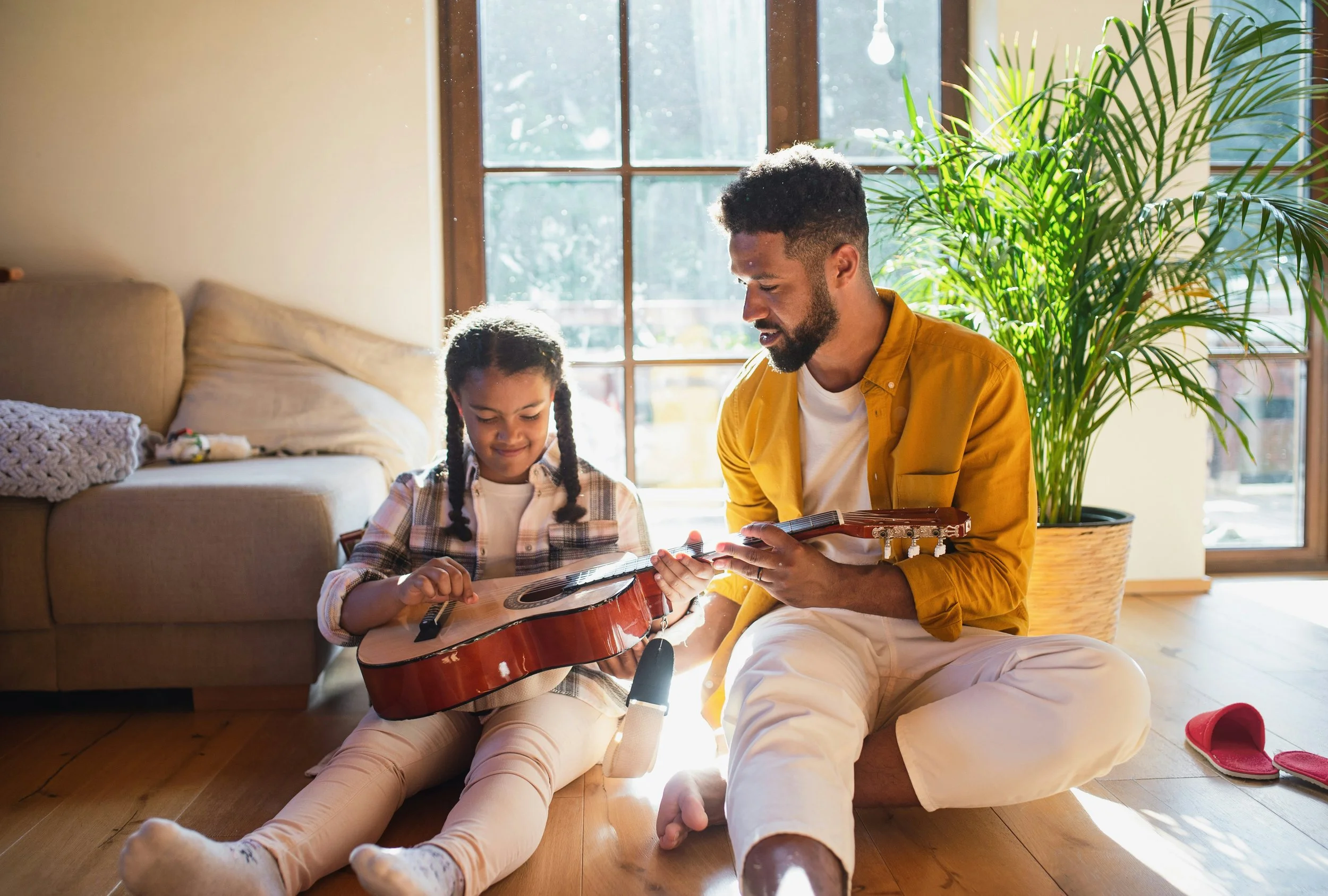 A dad and daughter enjoy a guitar lesson