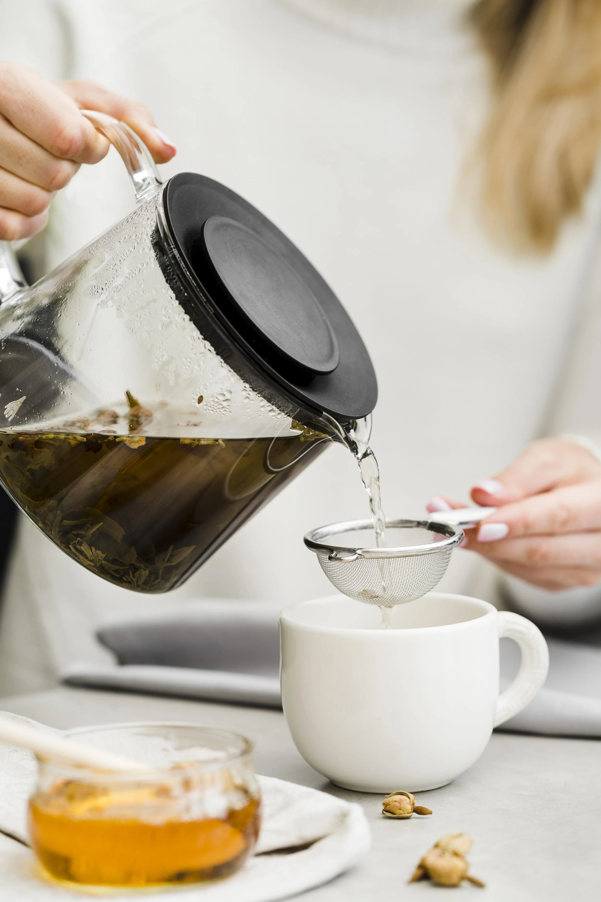 woman-pouring-tea-cup-from-tea-brewer-using-sieve.jpg