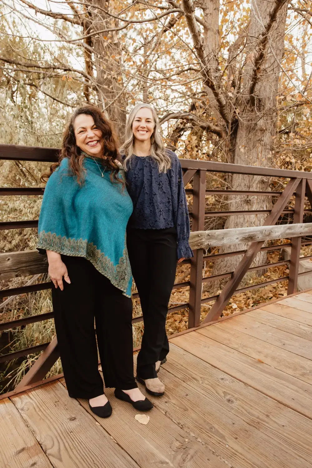 Gail & Shannon standing on a bridge in the woods