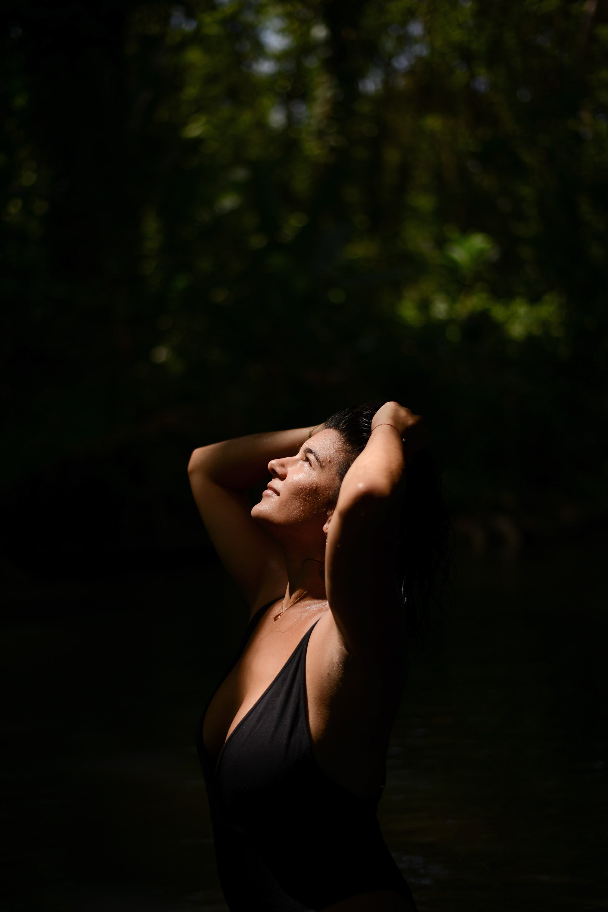 Femme pensant sous une lumière douce dans une nature sombre.