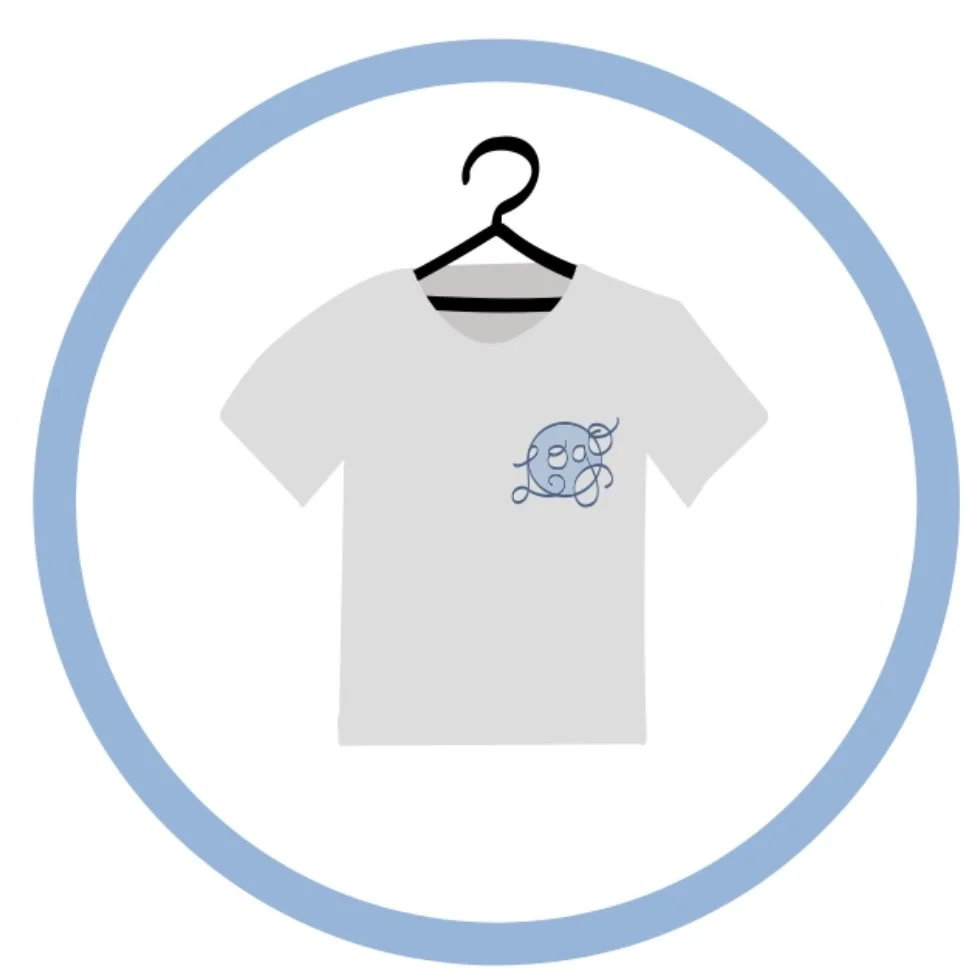A white t-shirt on a hanger with a blue embroidered monogram design on the left chest area, enclosed in a blue circle.