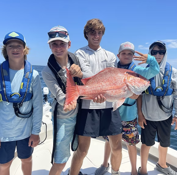 Group of young boys holding up a big red snapper