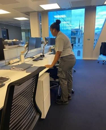 Office cleaner wiping desks and surfaces in a corporate office