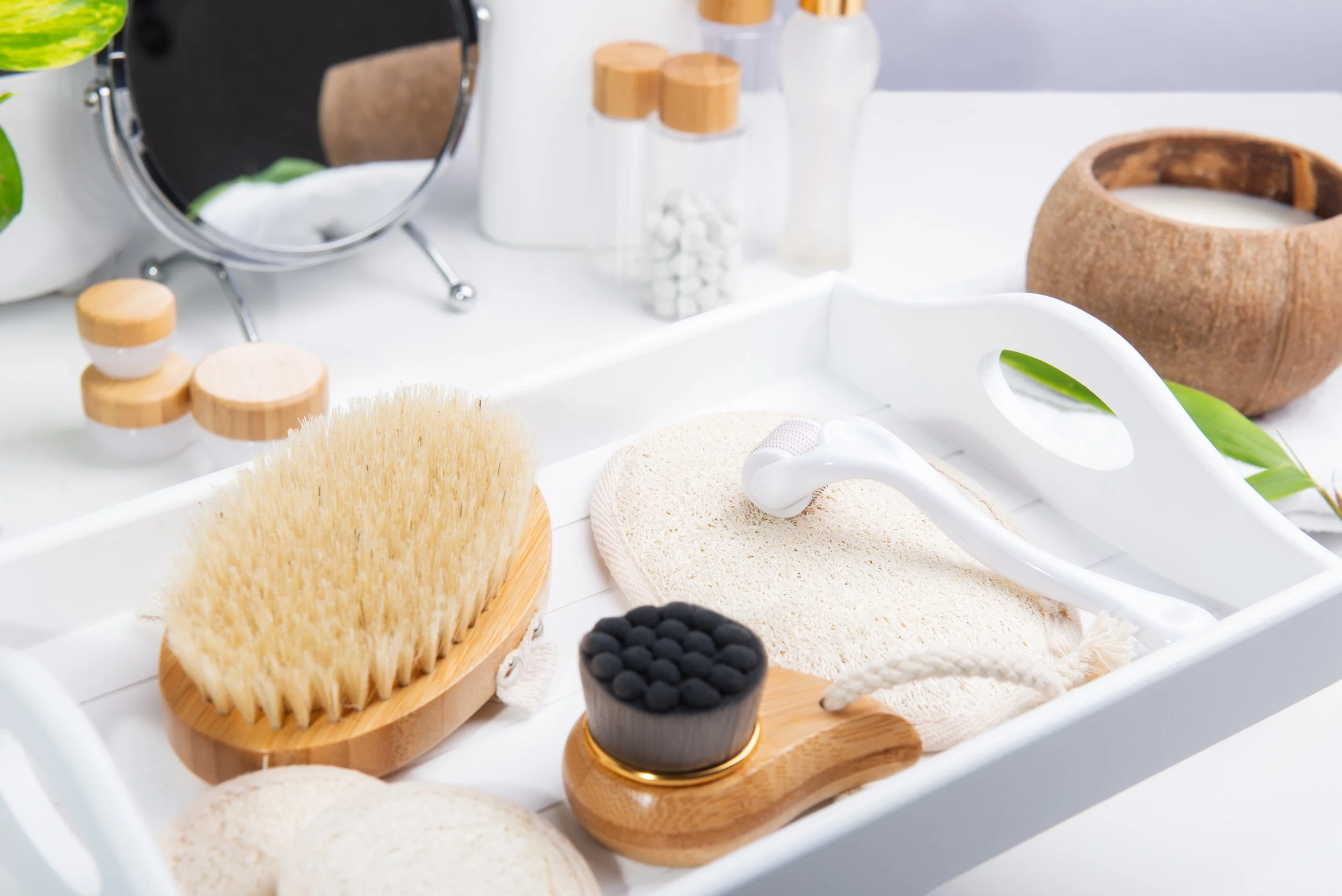 Spa or skincare tools including brushes, a pumice stone, a massager, and skincare products on a white tray.