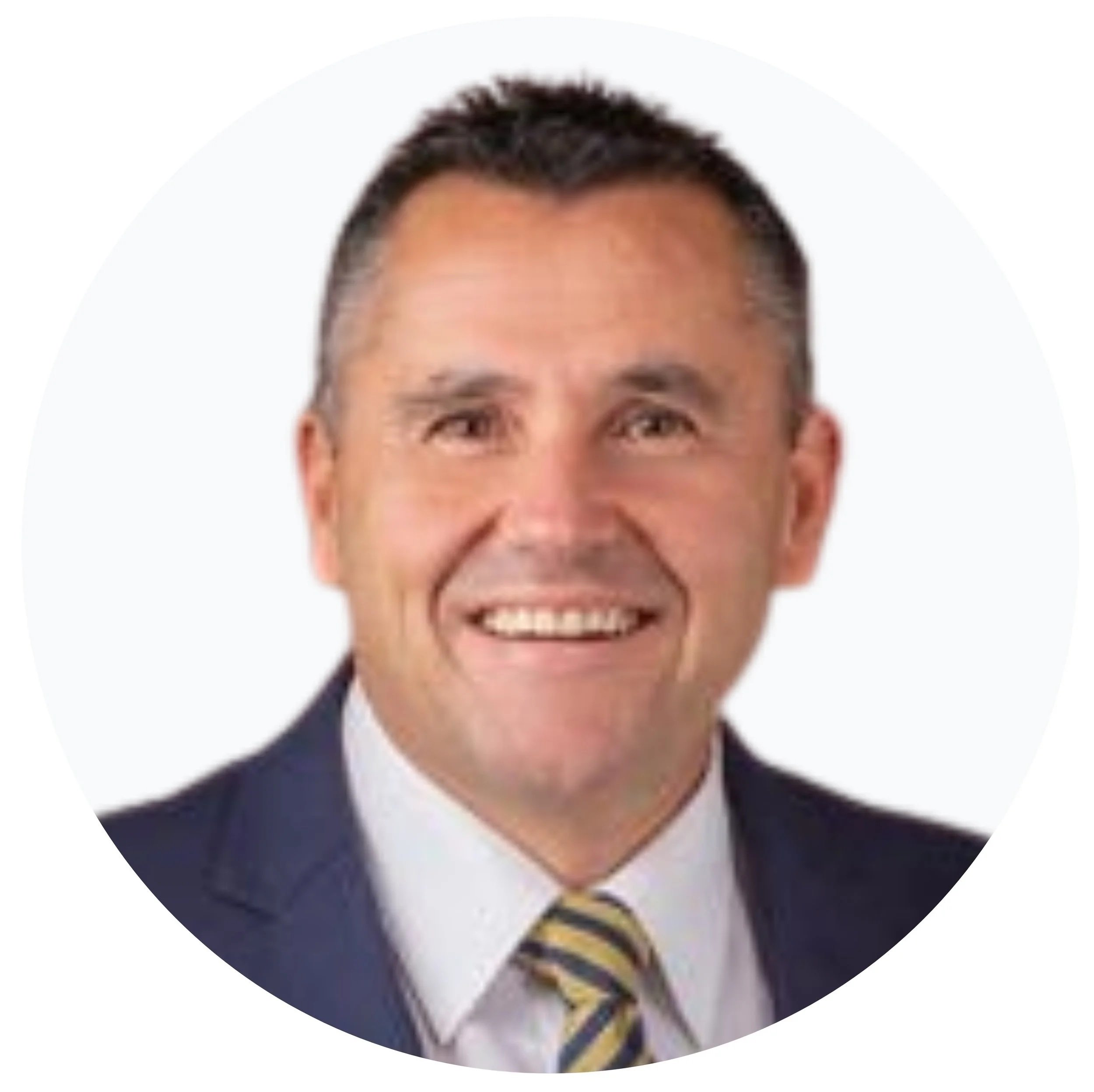 Smiling man in a suit and tie, headshot with a white background.