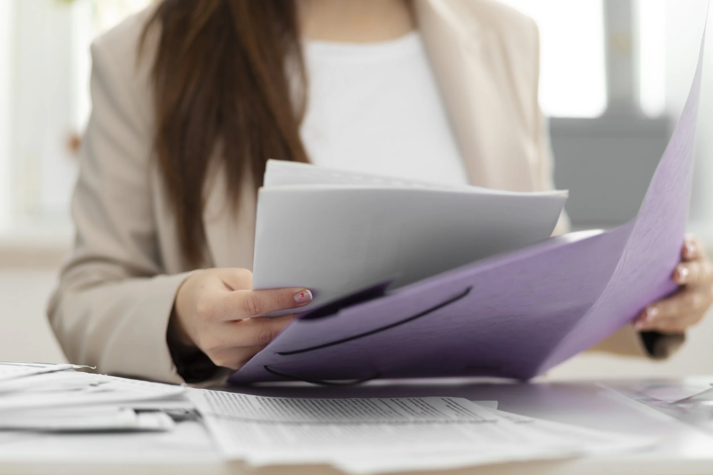 A professional sitting at a desk, placing documents into a folder.