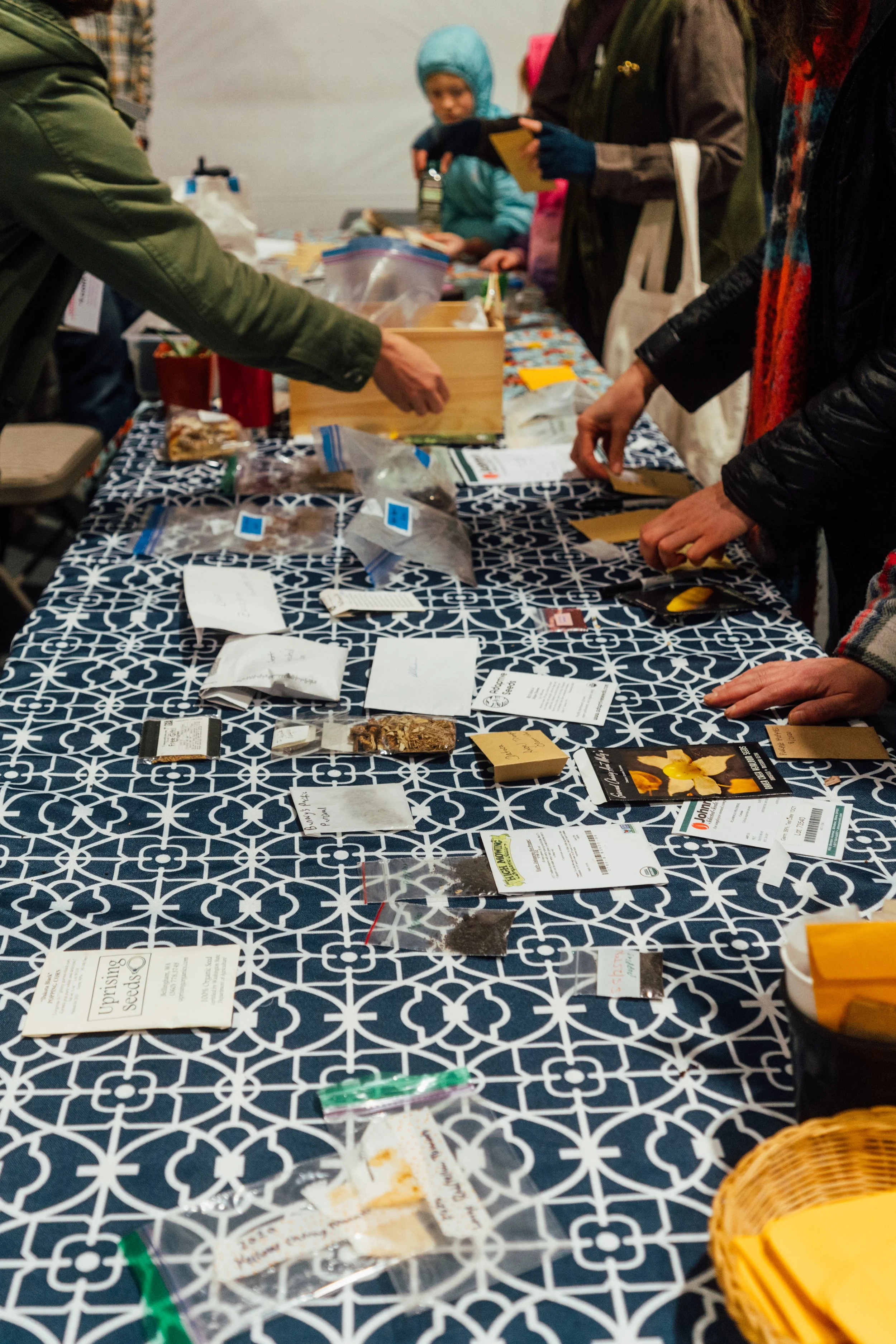 People gathered at a table with seeds, labels, and planting supplies for seed trading or planting event.