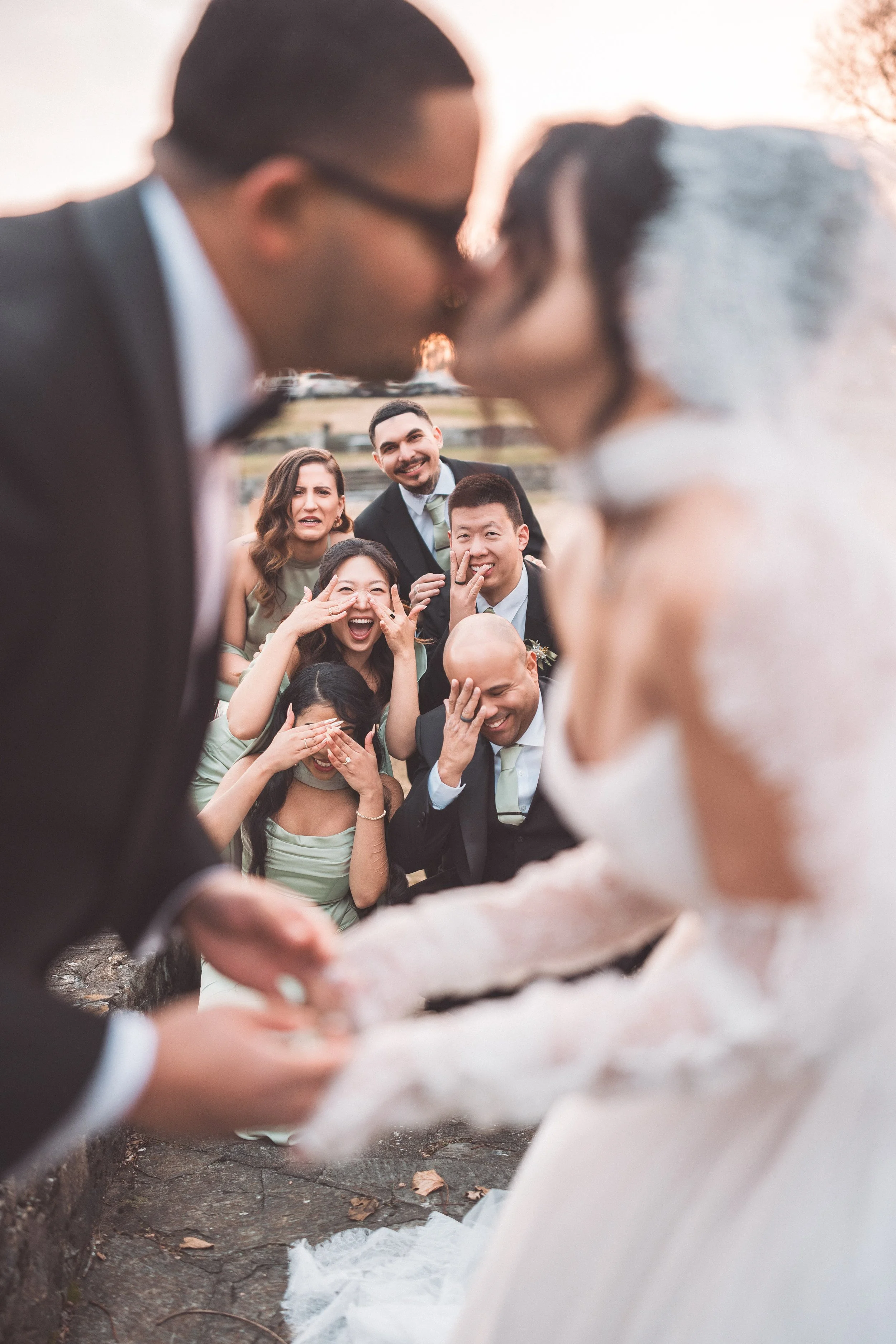 A wedding ceremony with a couple kissing and guests reacting with laughter and surprise in the background.