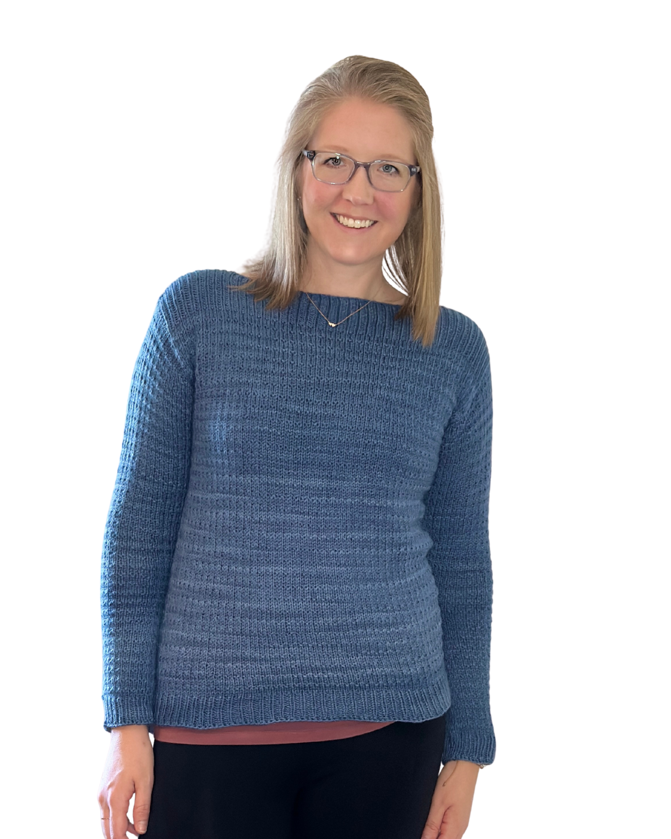 A woman with glasses and blonde hair wearing a blue sweater and black pants, smiling.