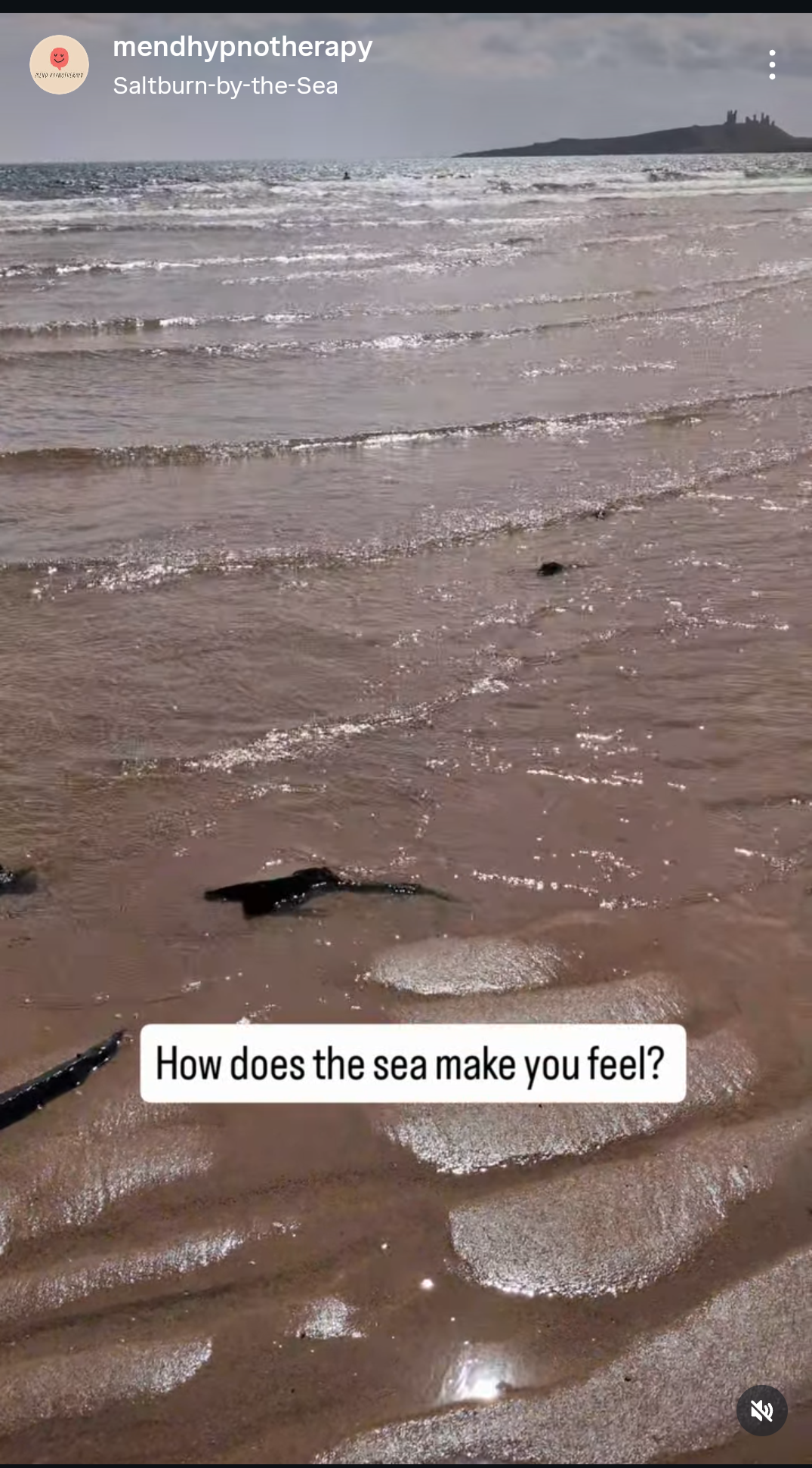 View of the ocean with waves reaching the sandy beach, with a small island or rocky formation in the distance. The image has a caption that reads, 'How does the sea make you feel?'