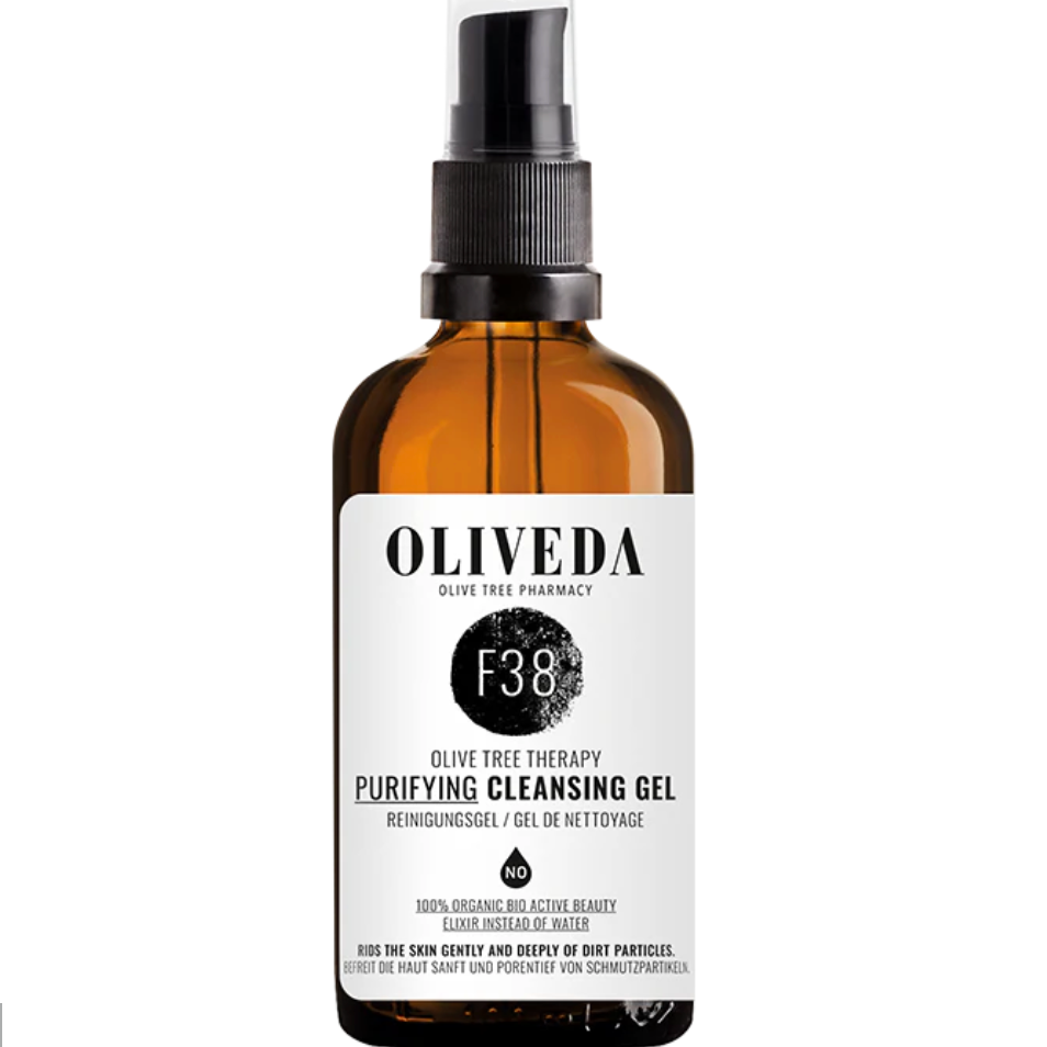 Amber glass spray bottle labeled 'Oliveda F38 Purifying Cleansing Gel' with black cap and spray nozzle.