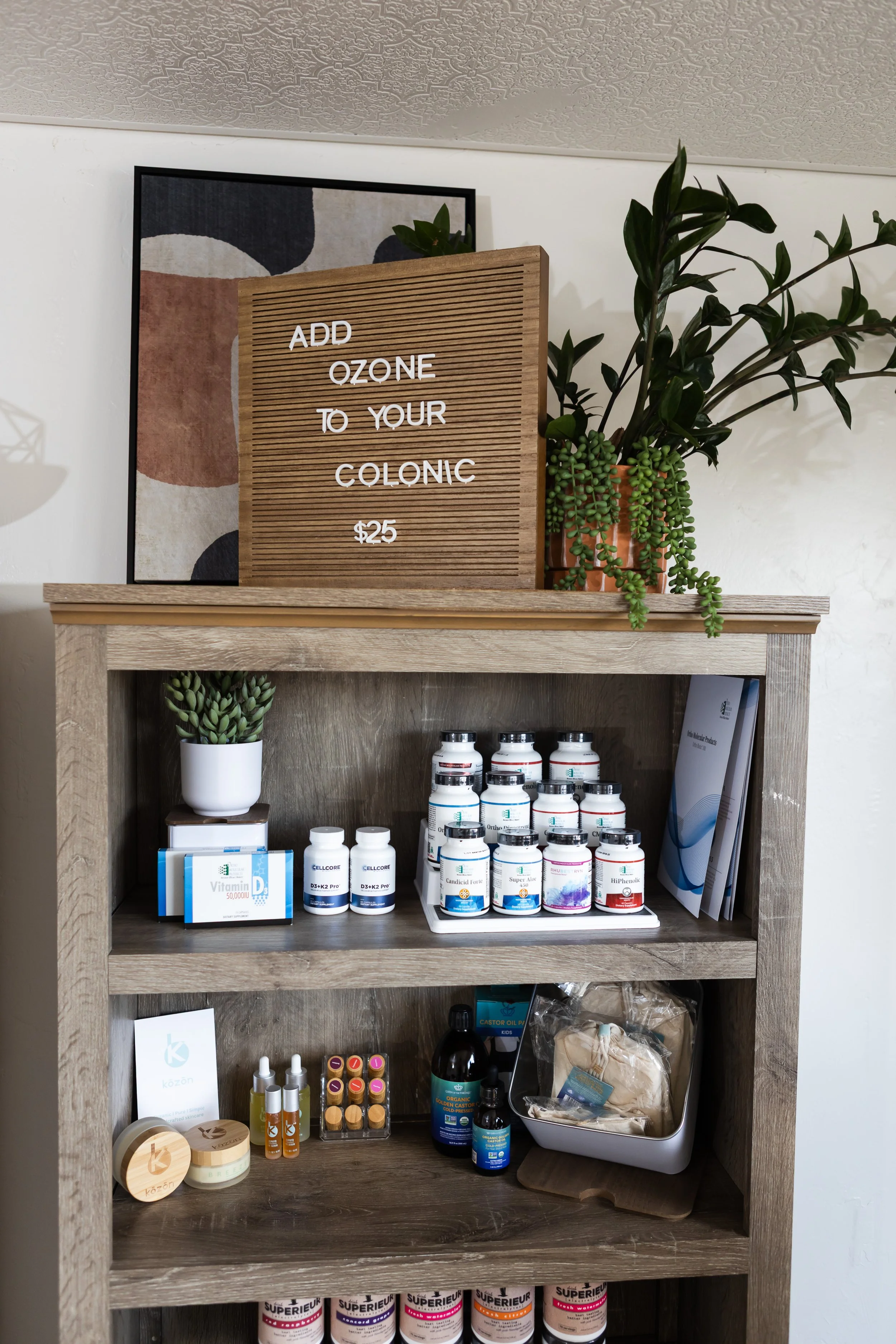 A wooden shelf displaying dietary supplements, skincare products, and informational brochures, with a sign offering ozone treatments to improve colon health for $25.