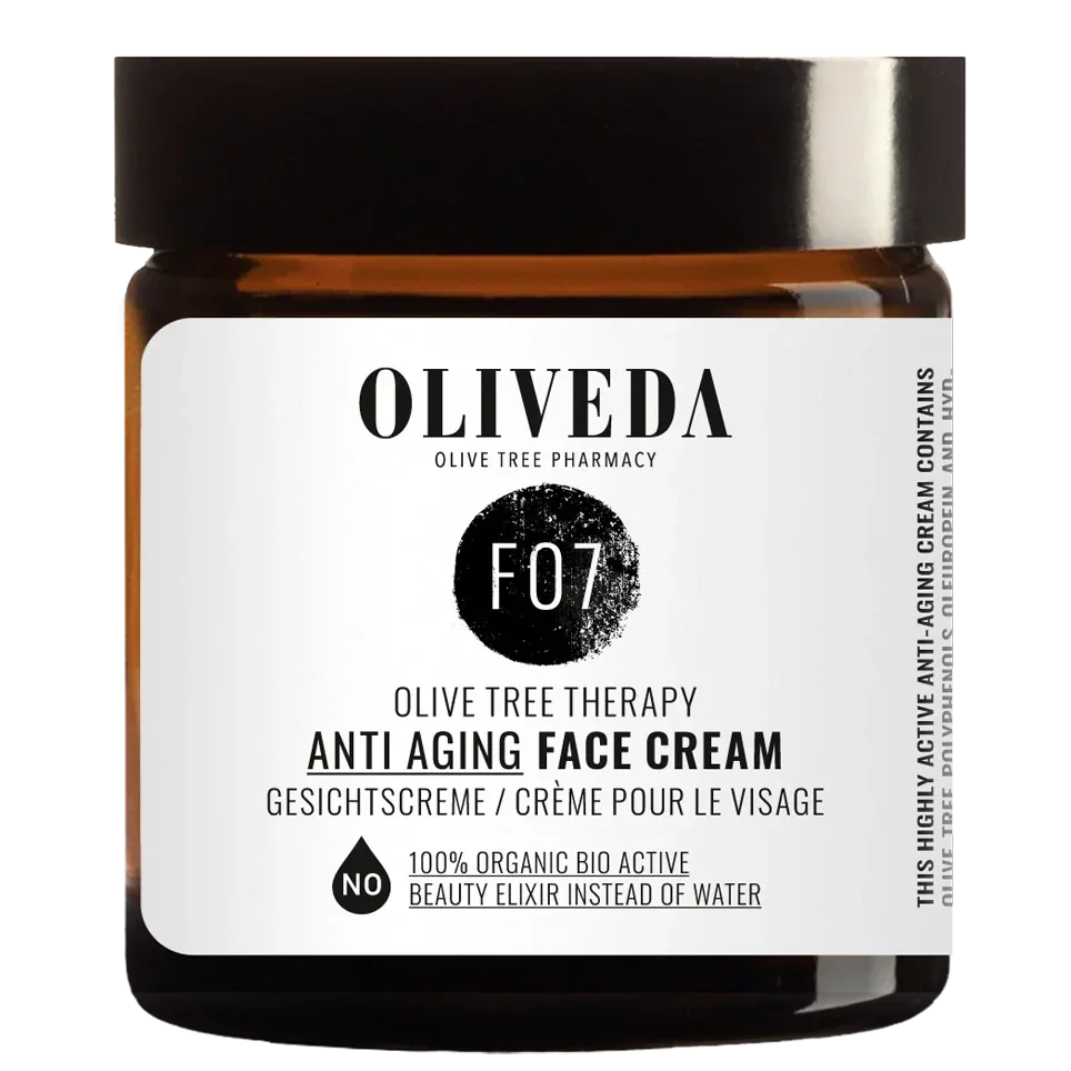 A jar of OLIVEDA Olive Tree Therapy Anti Aging Face Cream with a white label, black lid, and black text indicating it is made from organic ingredients and contains an active beauty elixir.