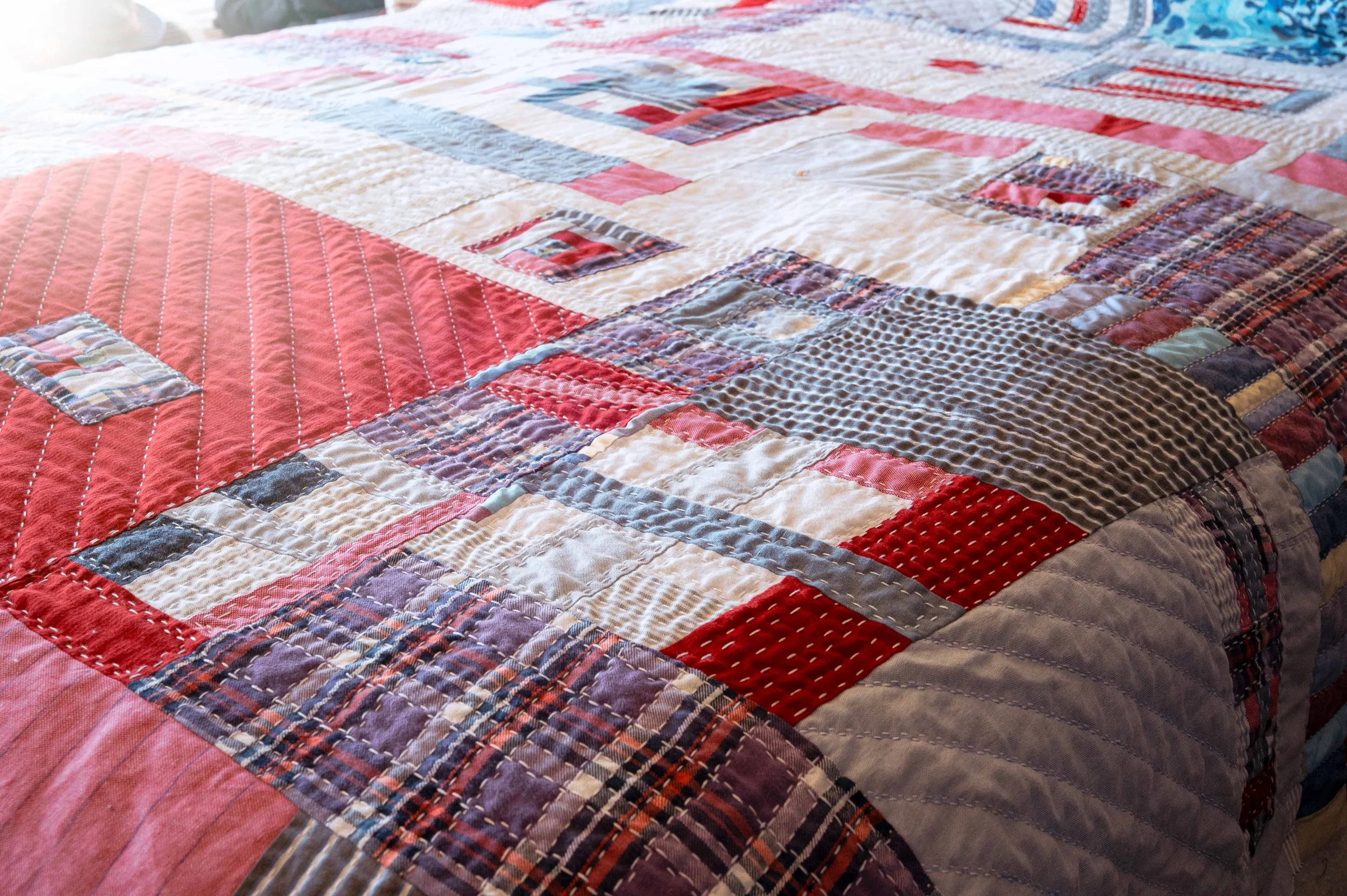Close-up of a patchwork quilt on a bed with various colorful fabric squares and patterns.